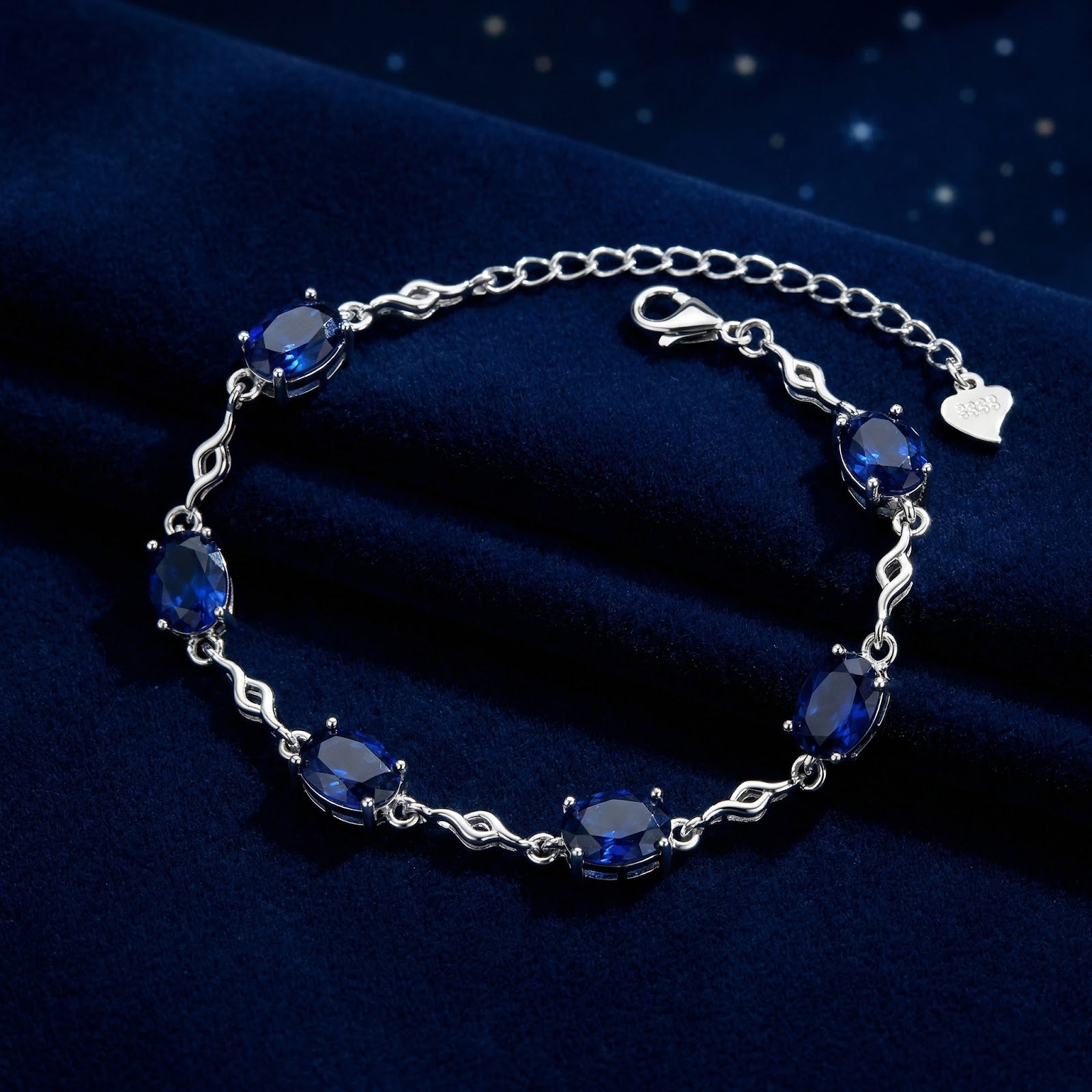 S925 sterling silver station bracelet with oval-cut simulated sapphires on a dark blue velvet background.