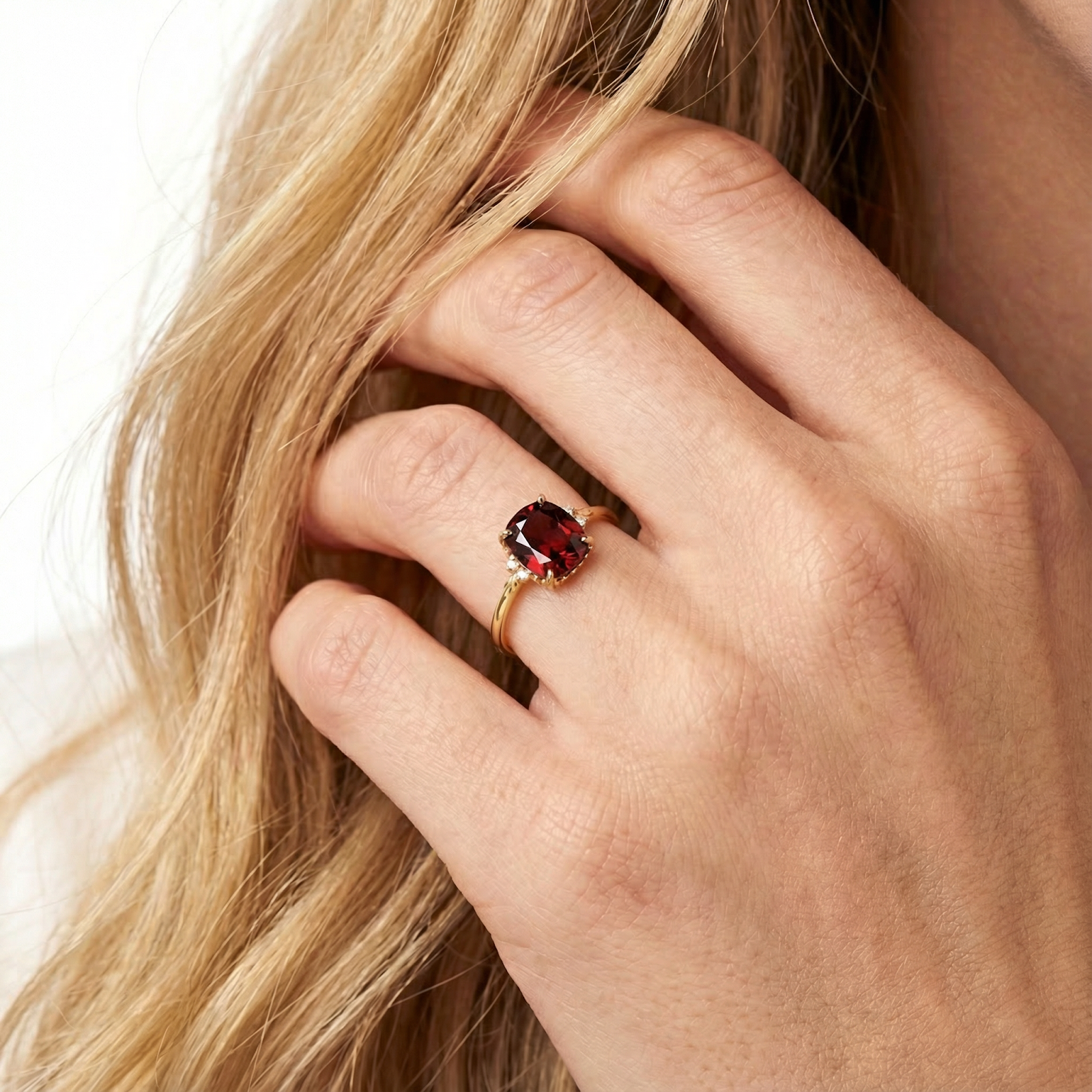Close-up of the Valerine 18K gold vermeil ring with a cushion cut simulated garnet worn on a model's hand.