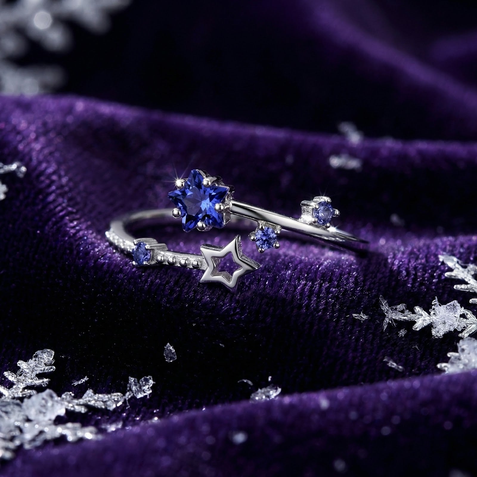 Star-cut blue simulated tanzanite bypass ring in sterling silver on purple velvet with decorative snowflakes.