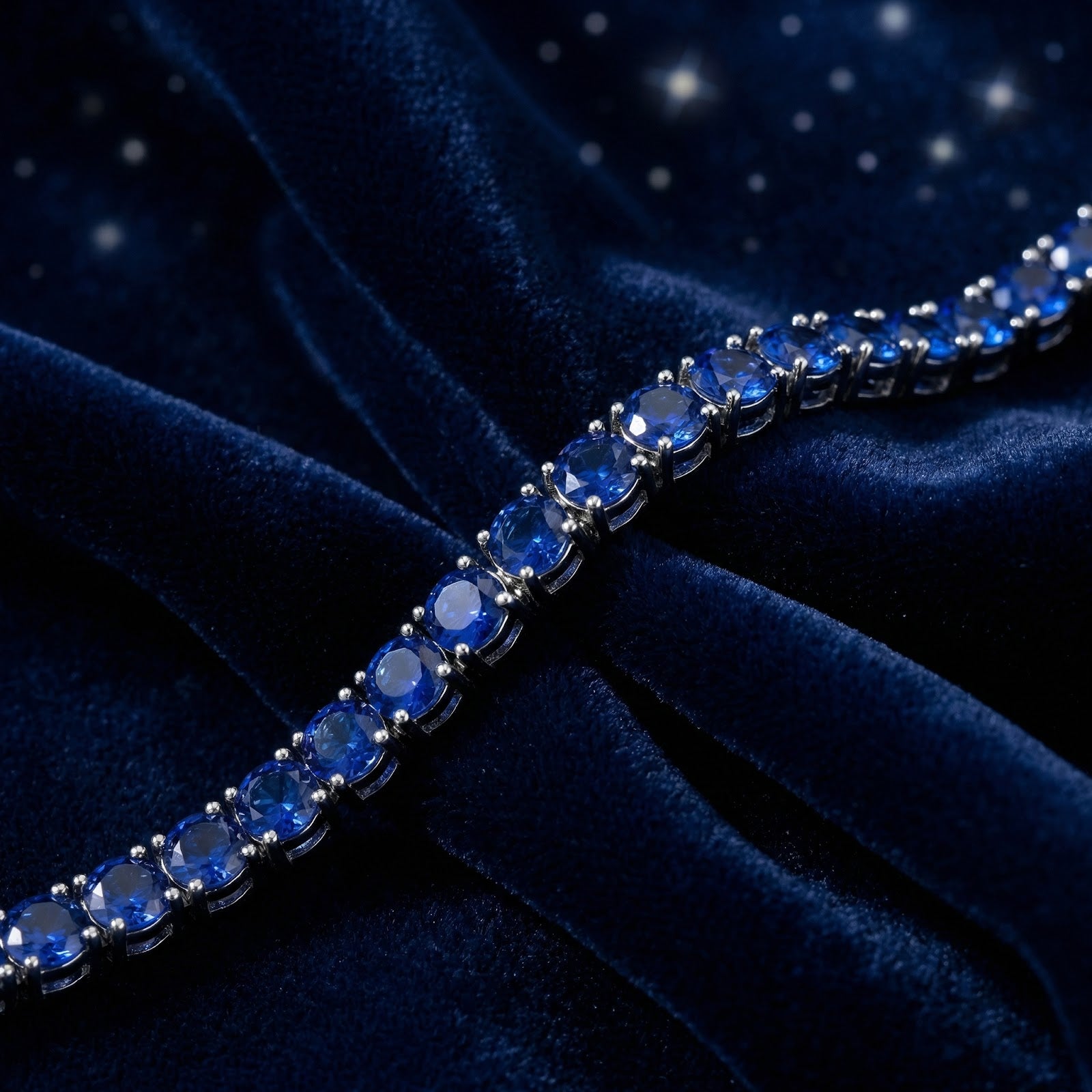 Close-up of round royal blue simulated sapphires in a silver stainless steel tennis bracelet setting.