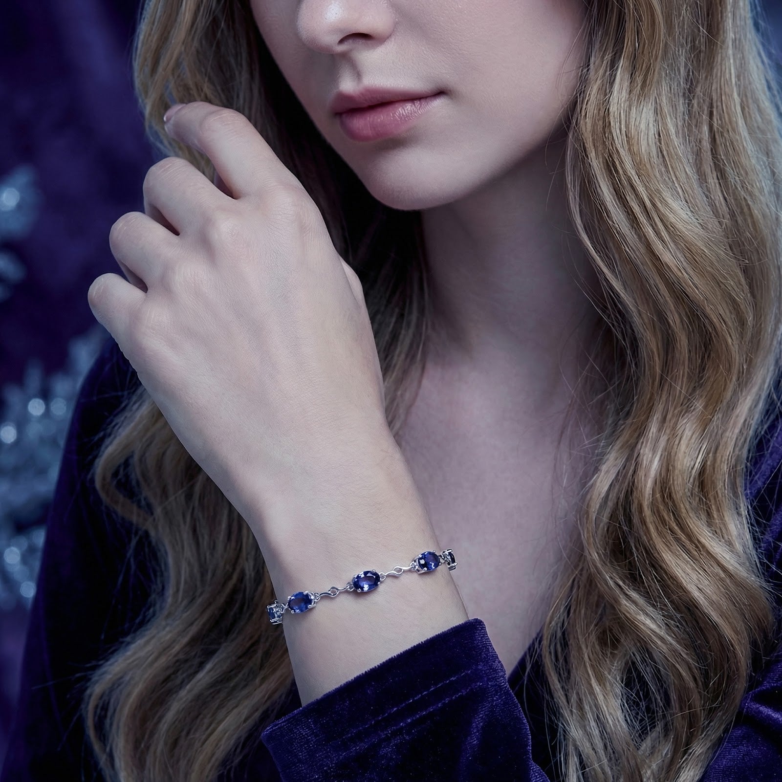 Woman wearing the Melisara sterling silver bracelet with oval-cut simulated tanzanite stones on her wrist.