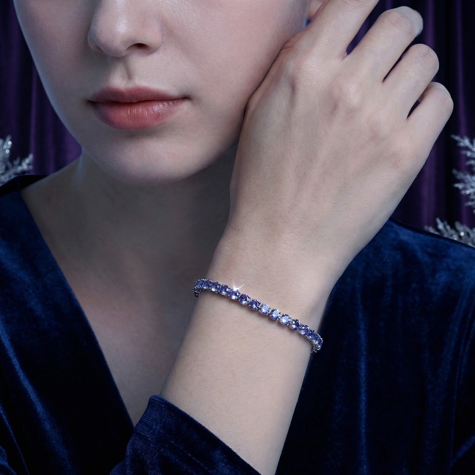 Close-up of the Lyrianne simulated tanzanite tennis bracelet in stainless steel worn on a woman's wrist.