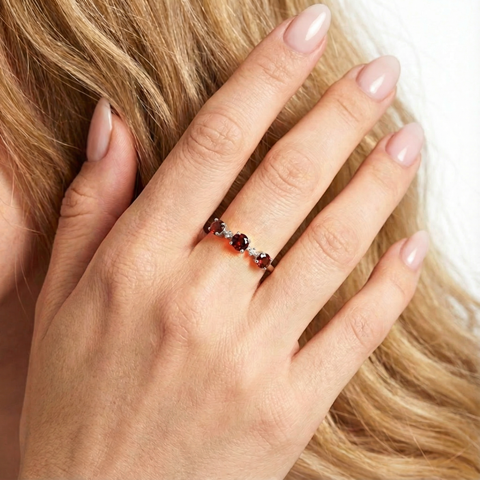 Close-up of the S925 sterling silver bypass ring with round red garnets on a hand for scale.