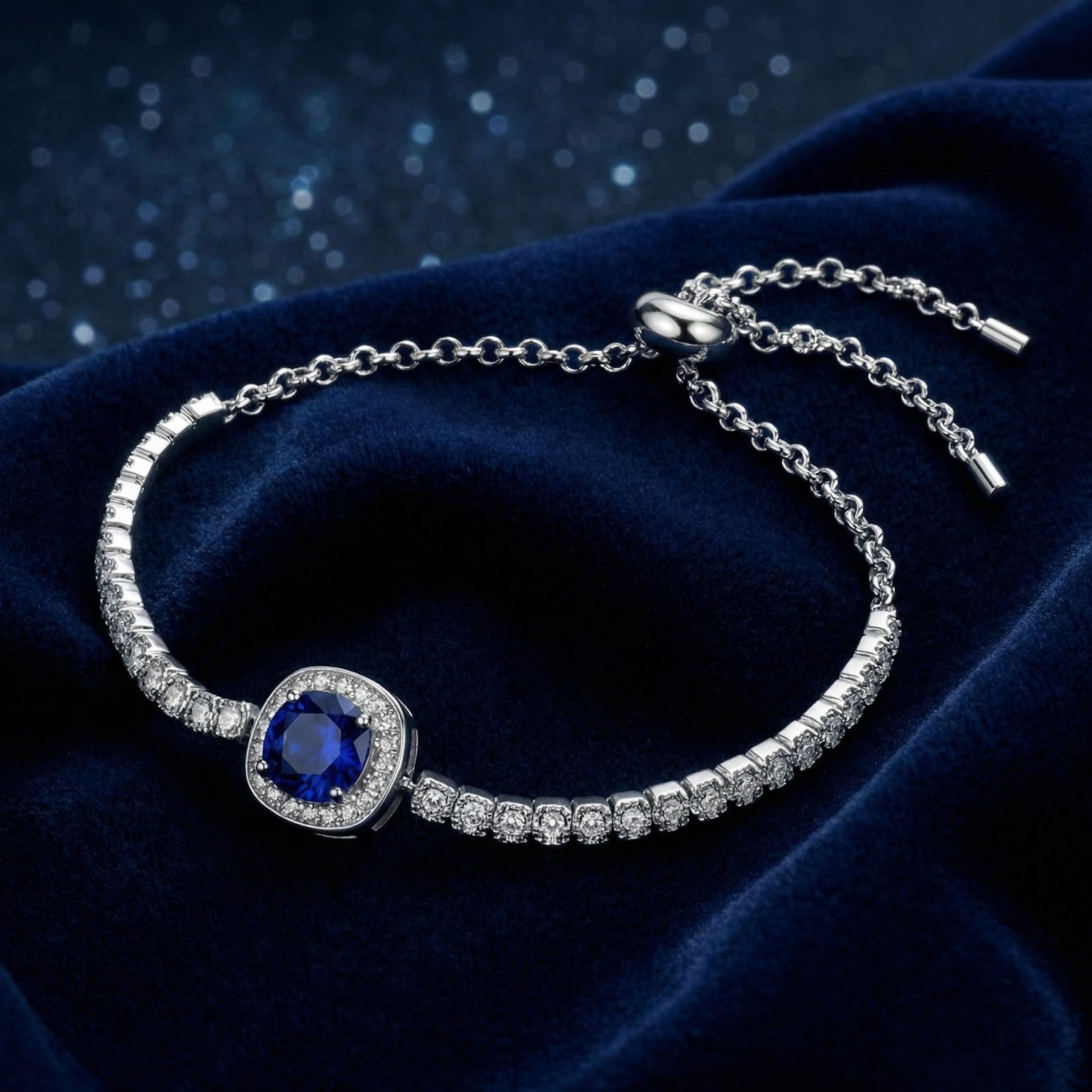 Sterling silver bolo bracelet with a round-cut simulated sapphire halo on a blue velvet background.