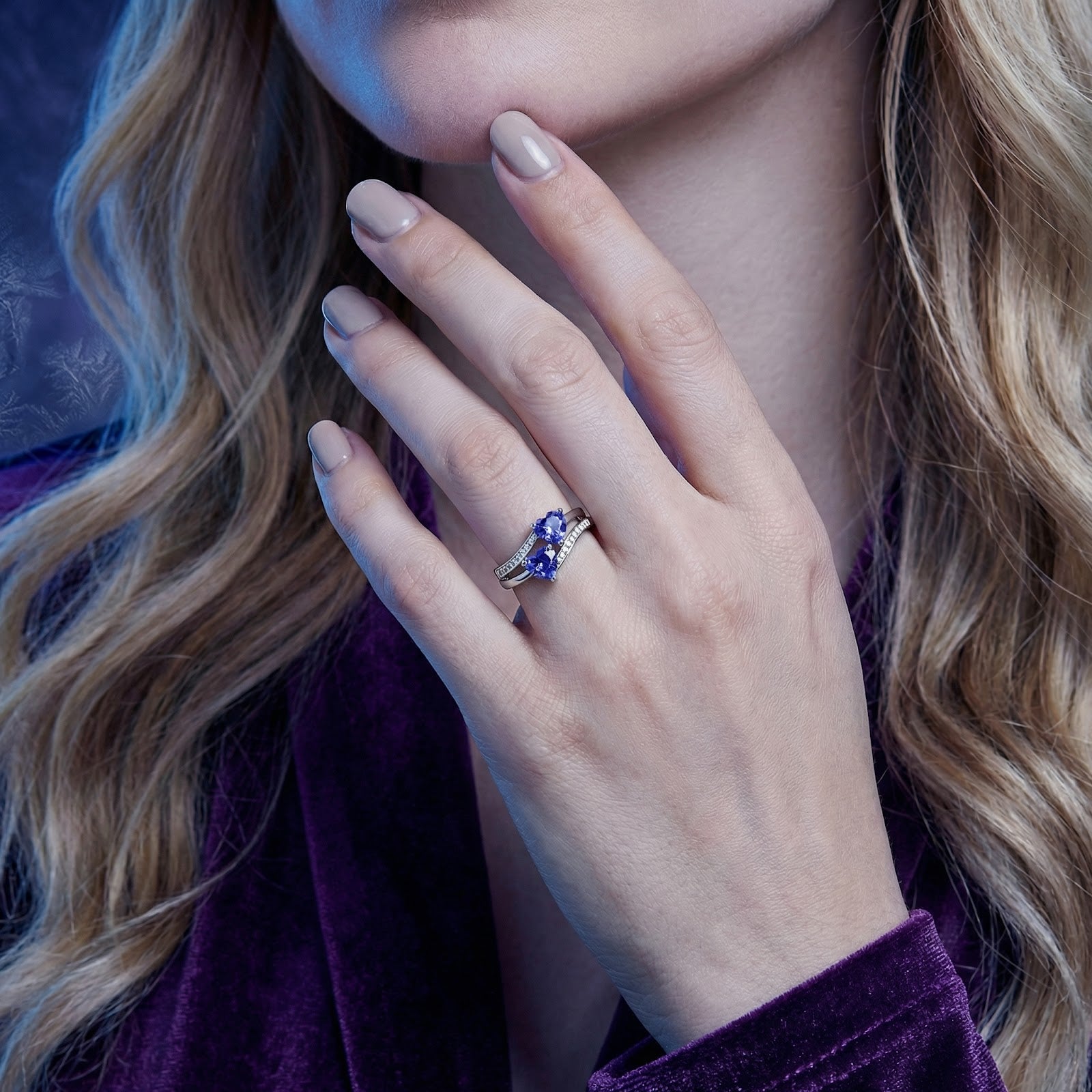 Model wearing the Adalienne S925 sterling silver ring with two heart-cut blue simulated tanzanite stones.