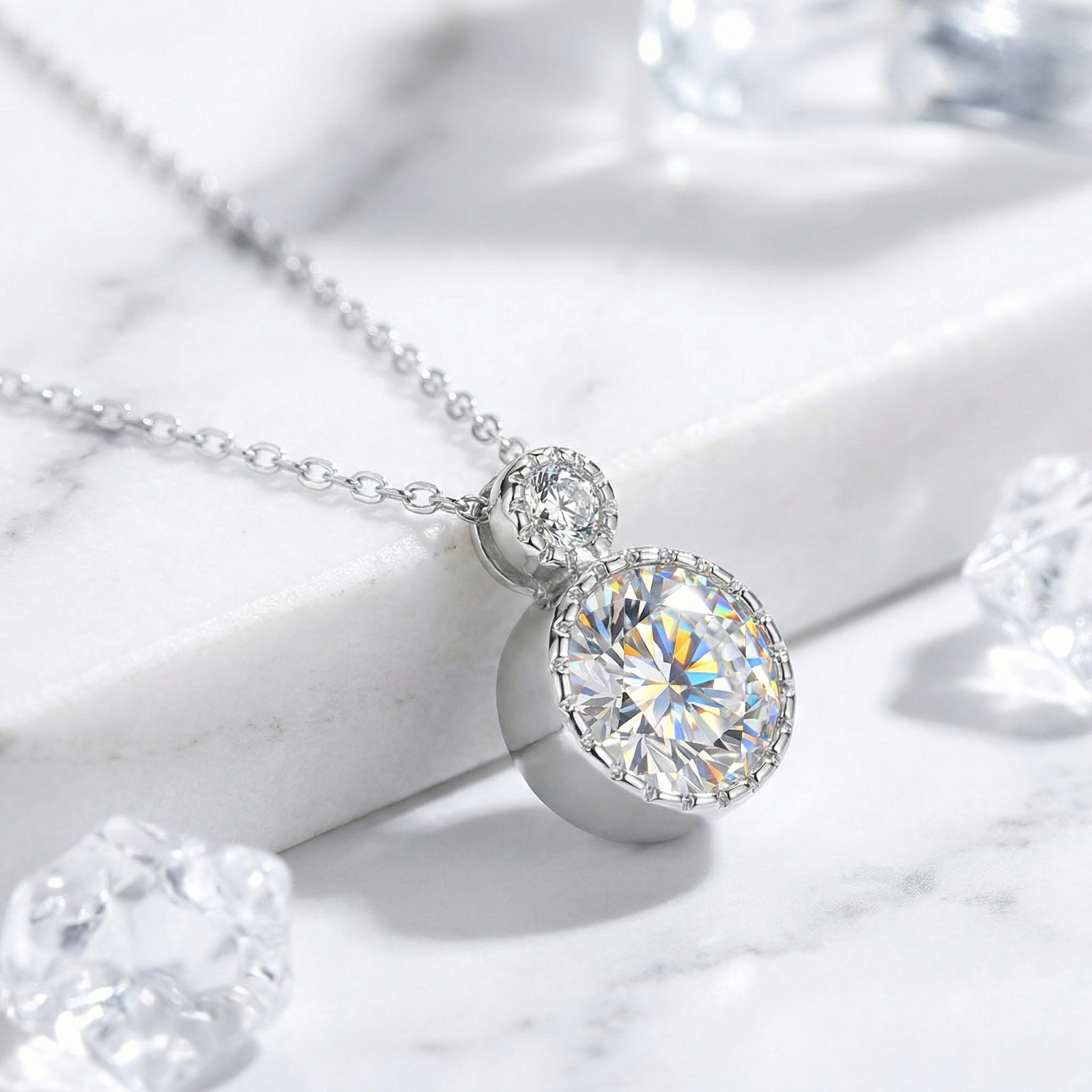 Side view of the sterling silver double-drop pendant showing the bezel-set round simulated diamonds on marble.