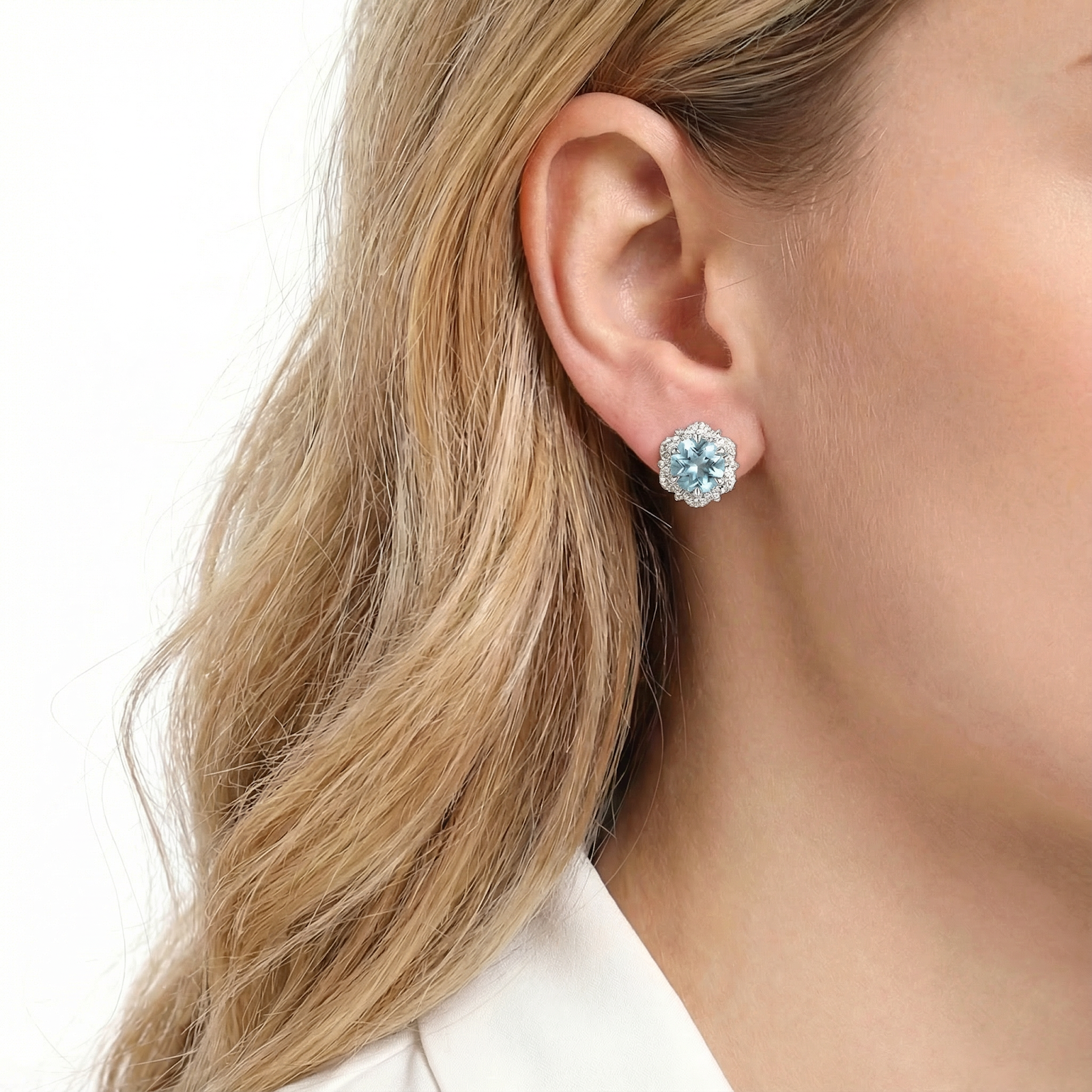 March birthstone simulated aquamarine halo stud earring in S925 sterling silver worn on a woman's ear.