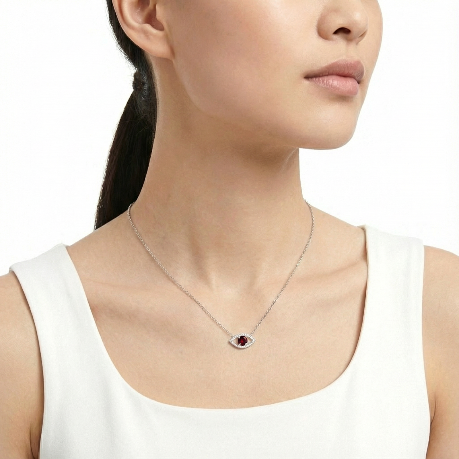 Sterling silver eye-shaped necklace with a red garnet stone worn by a model against a clean white background.