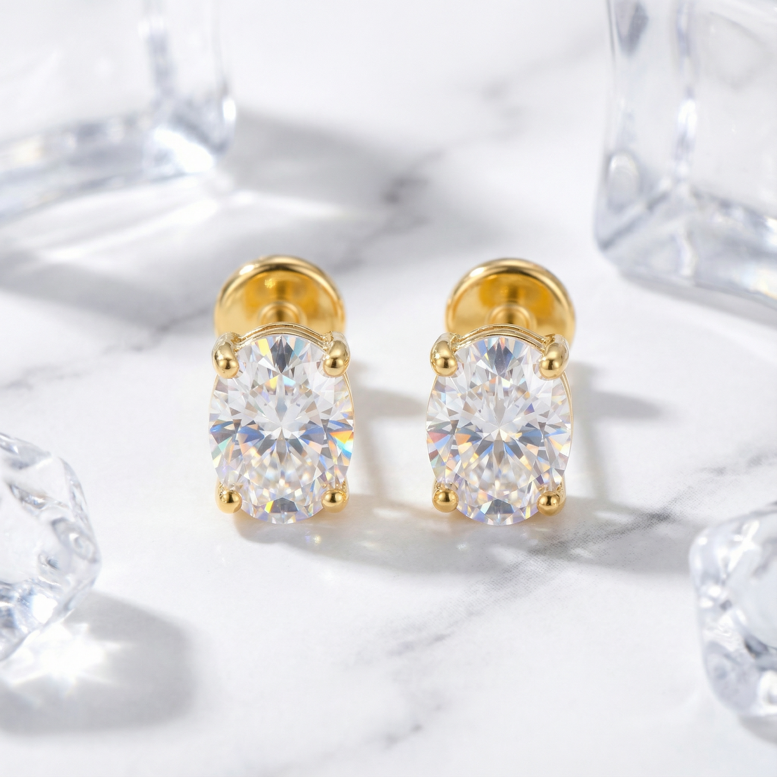 Front view of a pair of oval cut zirconia stud earrings in 18K gold vermeil on marble.
