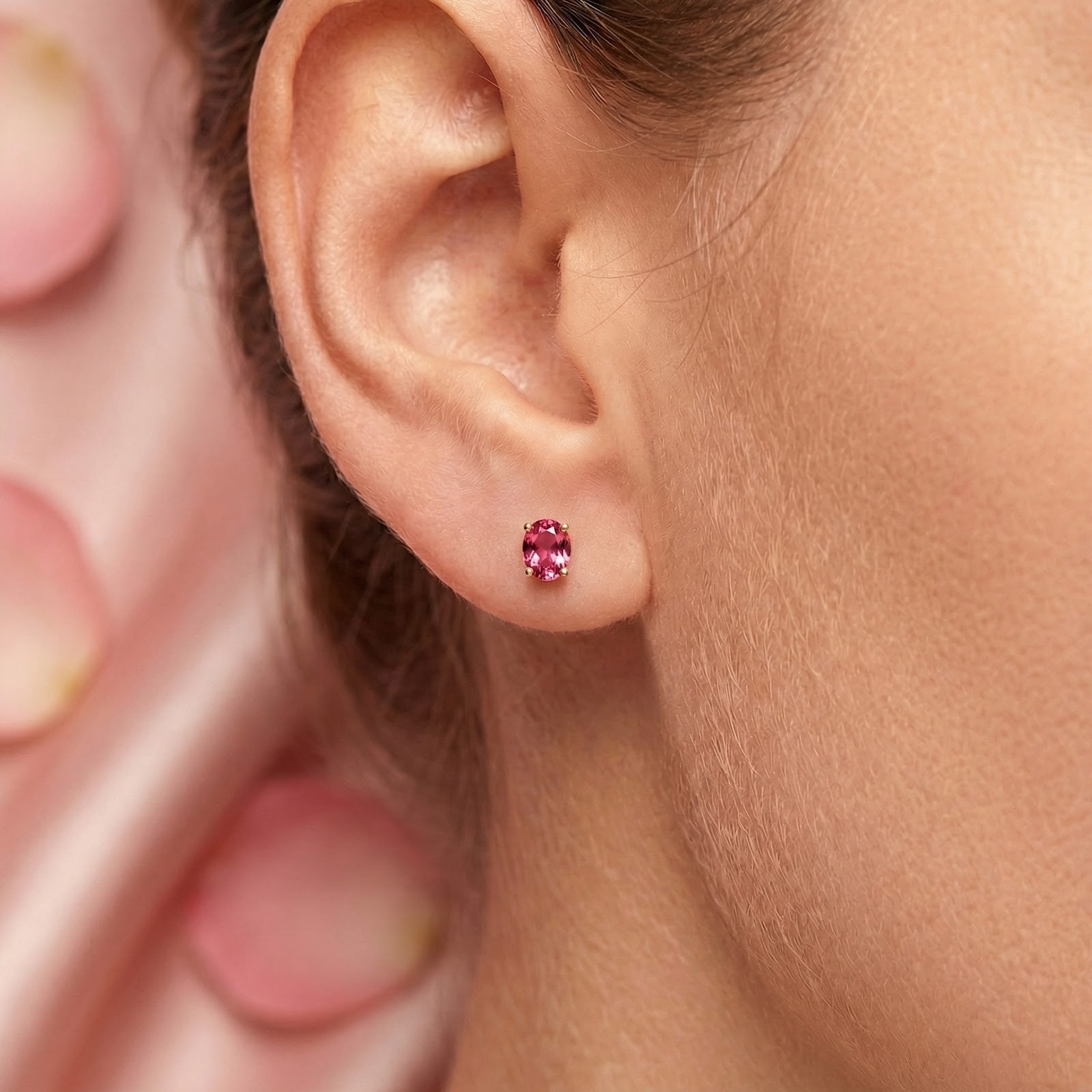 Close-up of an oval simulated pink tourmaline stud earring in 18K gold vermeil worn on a model's ear.