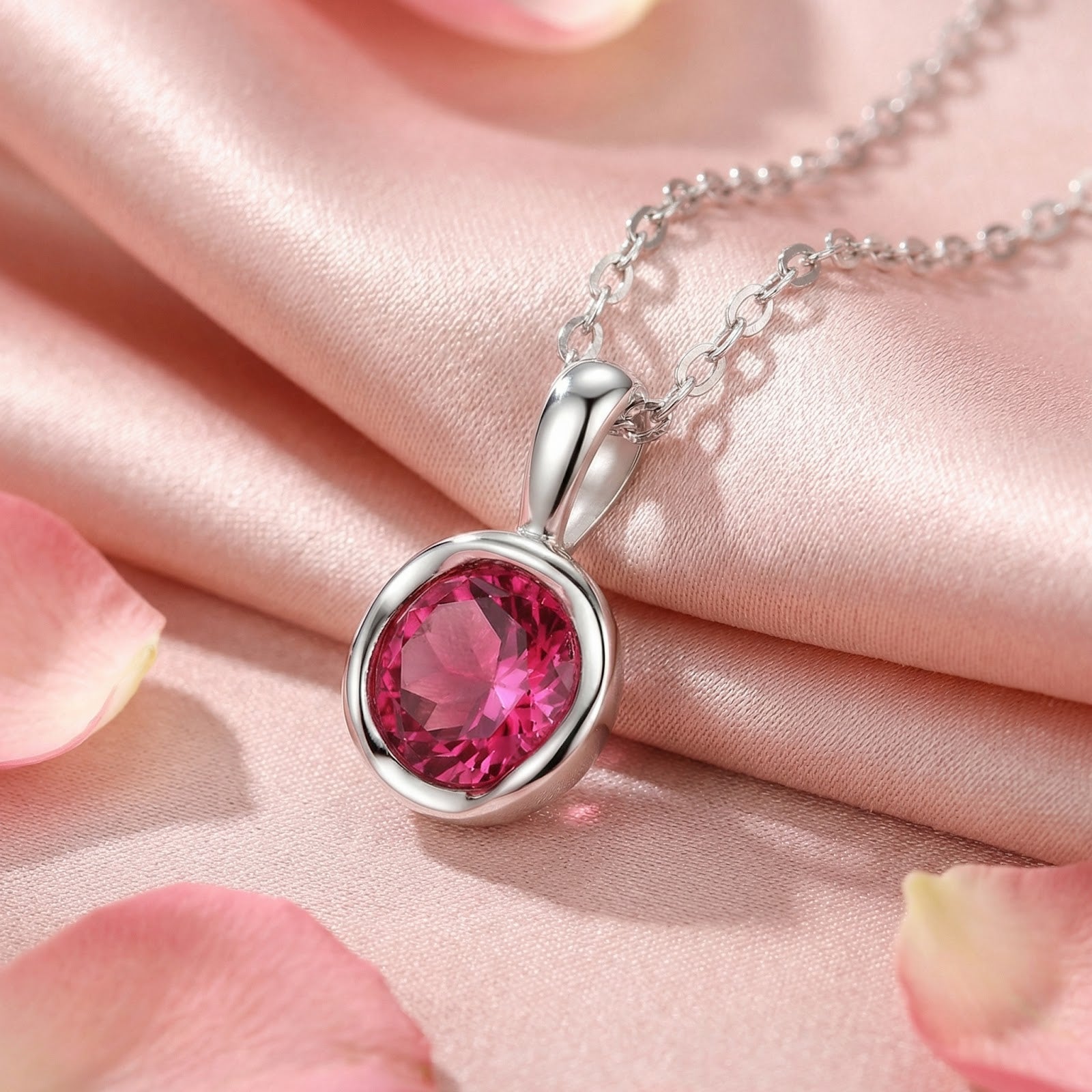 Round cut simulated pink tourmaline solitaire necklace in S925 sterling silver on pink silk with rose petals.