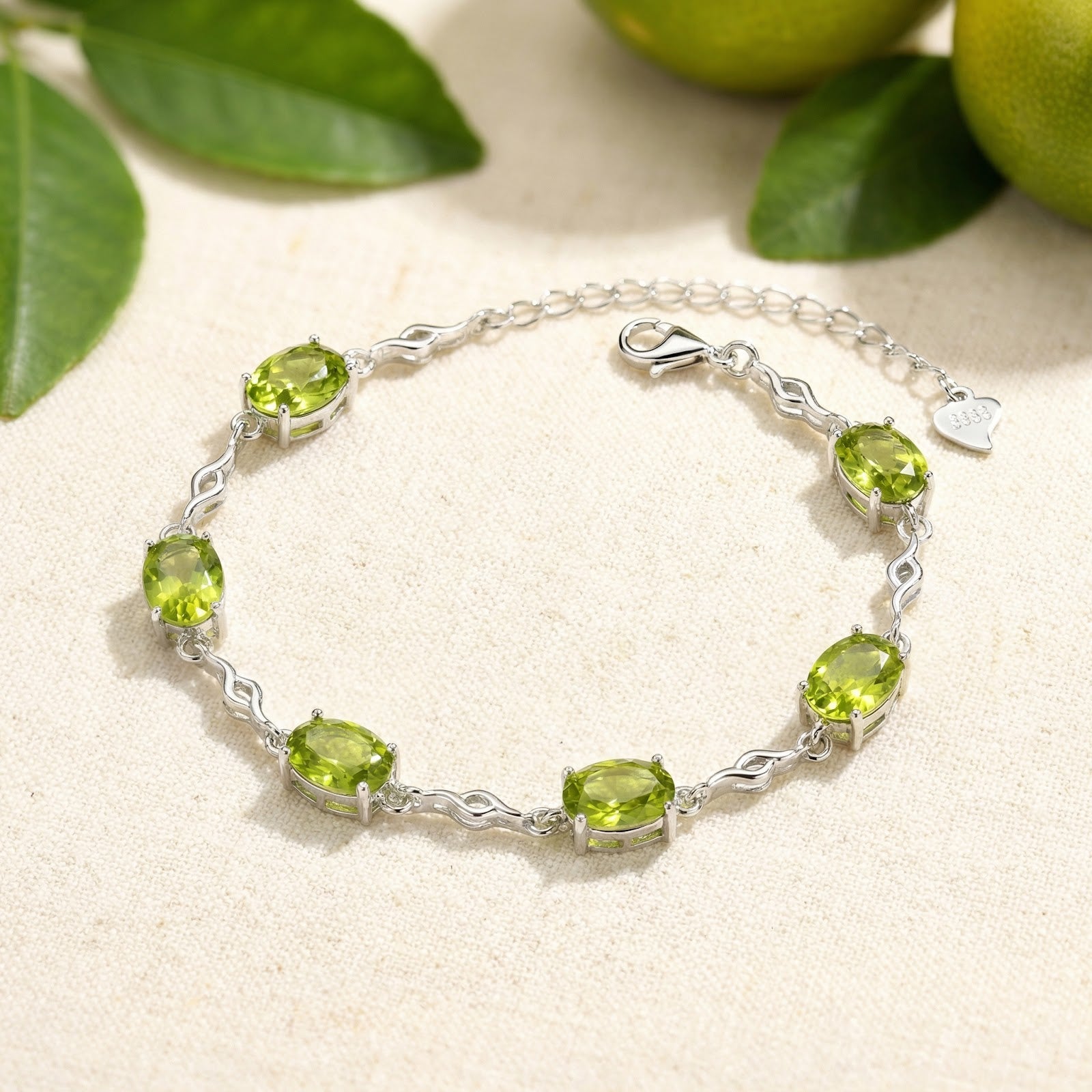 Sterling silver station bracelet featuring oval cut simulated peridot stones on a neutral lifestyle background.