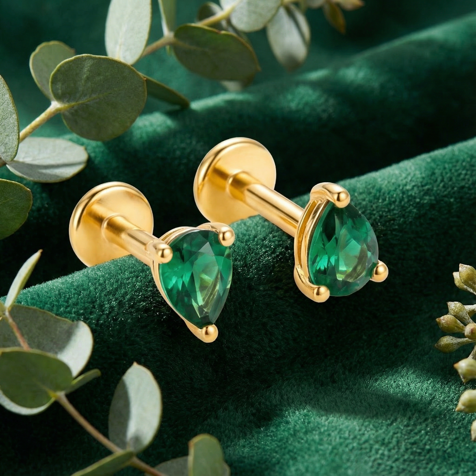 Detail view of pear-cut simulated emerald earrings in 18K gold vermeil with flat-back labret posts.