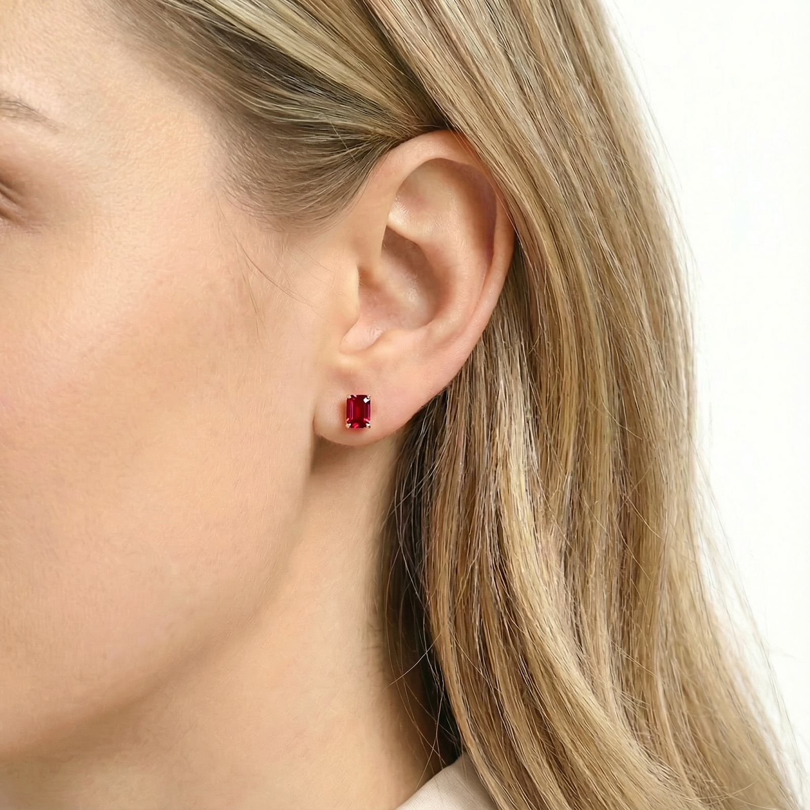 Side view of a model wearing an emerald-cut pigeon blood simulated ruby stud earring in 18K gold vermeil.