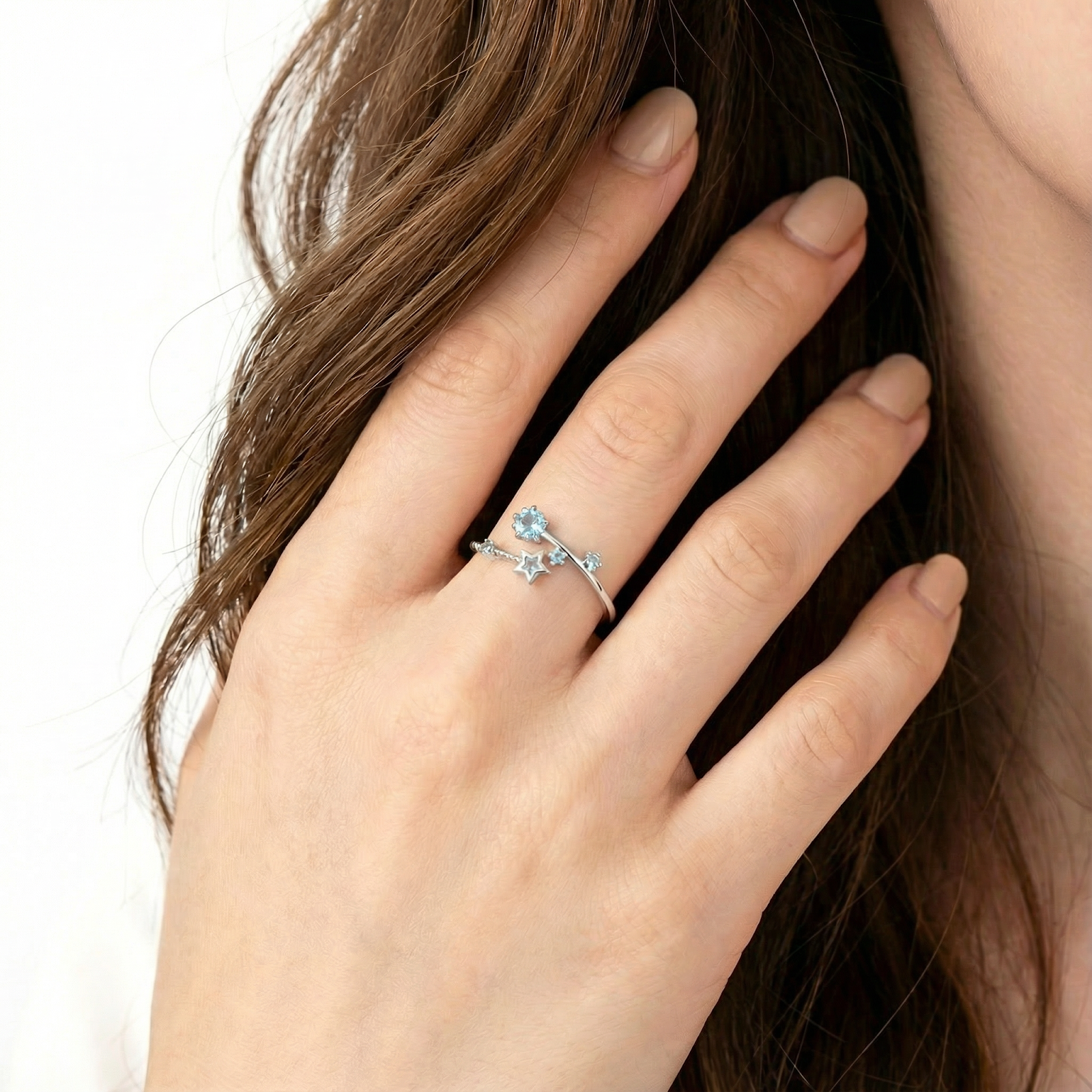 Model wearing the sterling silver Stella bypass ring with simulated aquamarine stars on her ring finger.