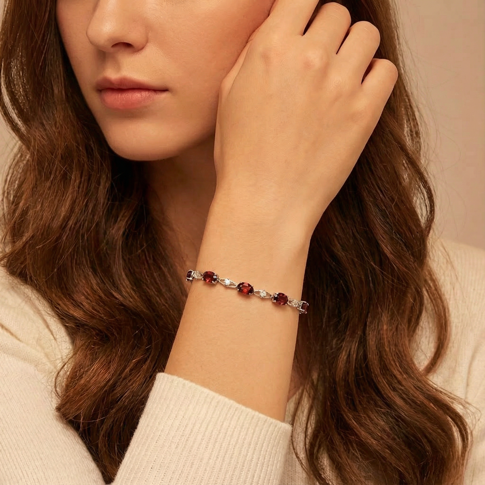 Thalassa helix bracelet with oval red simulated garnets in sterling silver worn on a woman's wrist.