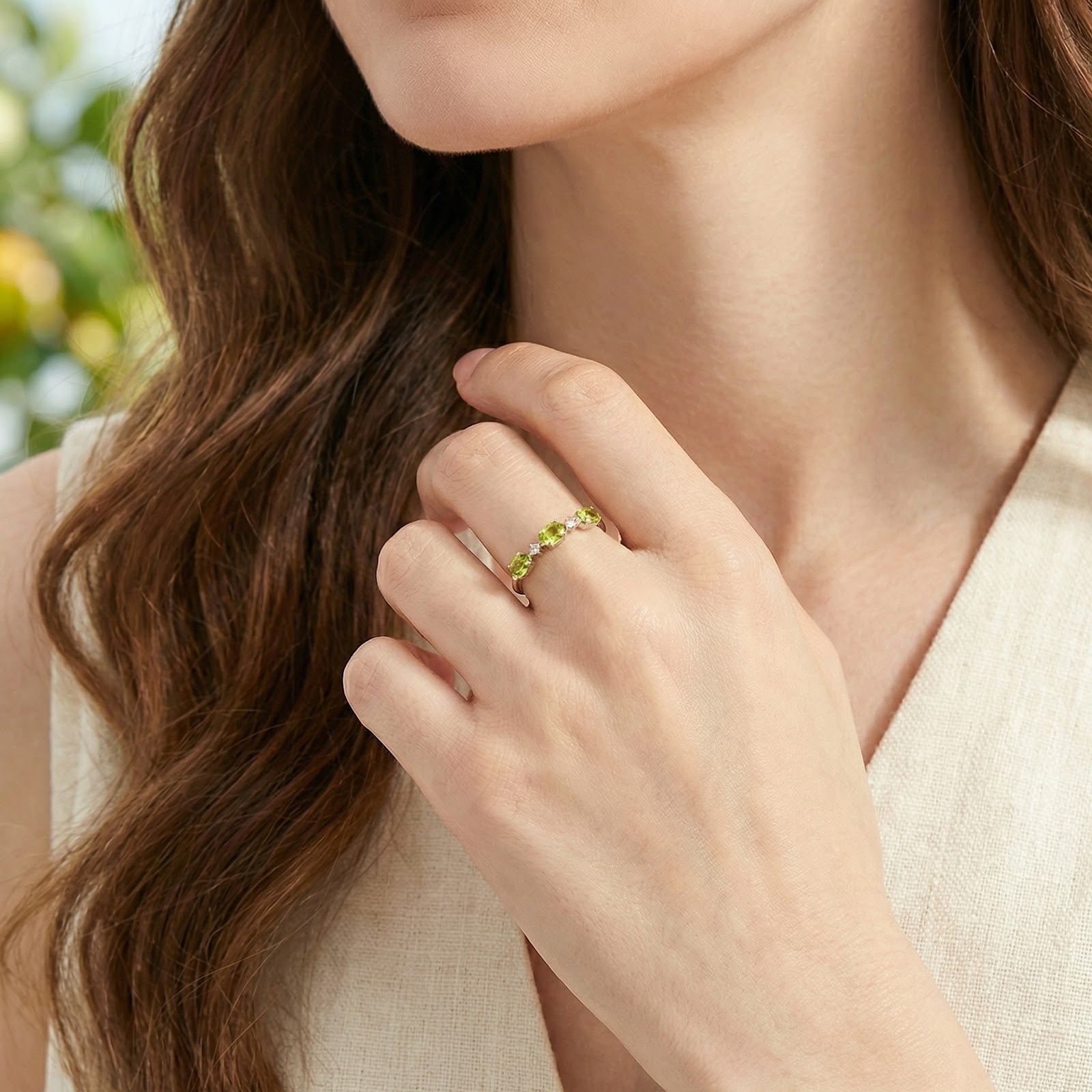 Model wearing the S925 sterling silver Mirabelle bypass ring with green simulated peridots against a linen shirt.