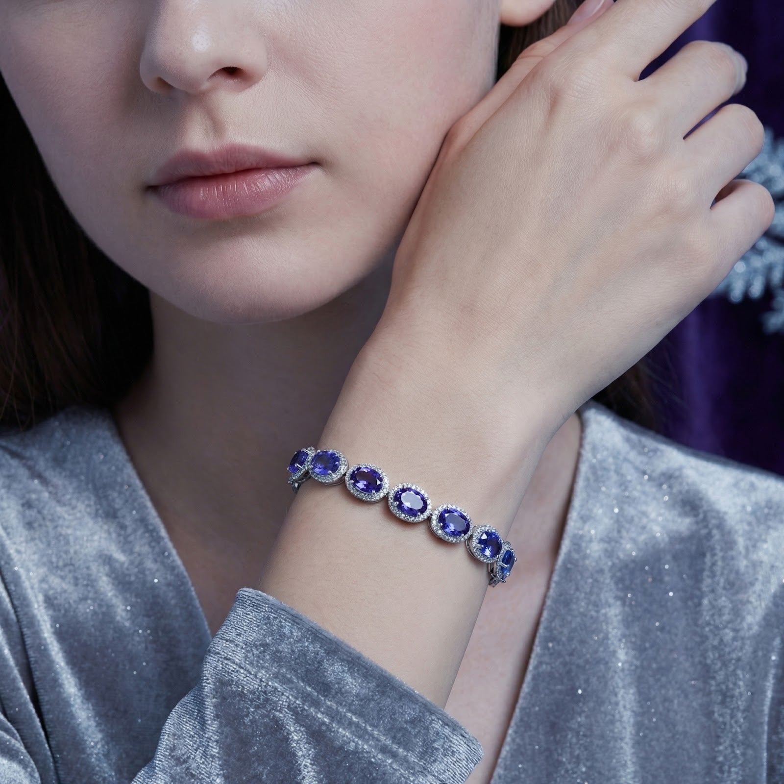 Model wearing a sterling silver tennis bracelet with oval blue-violet simulated tanzanite stones.