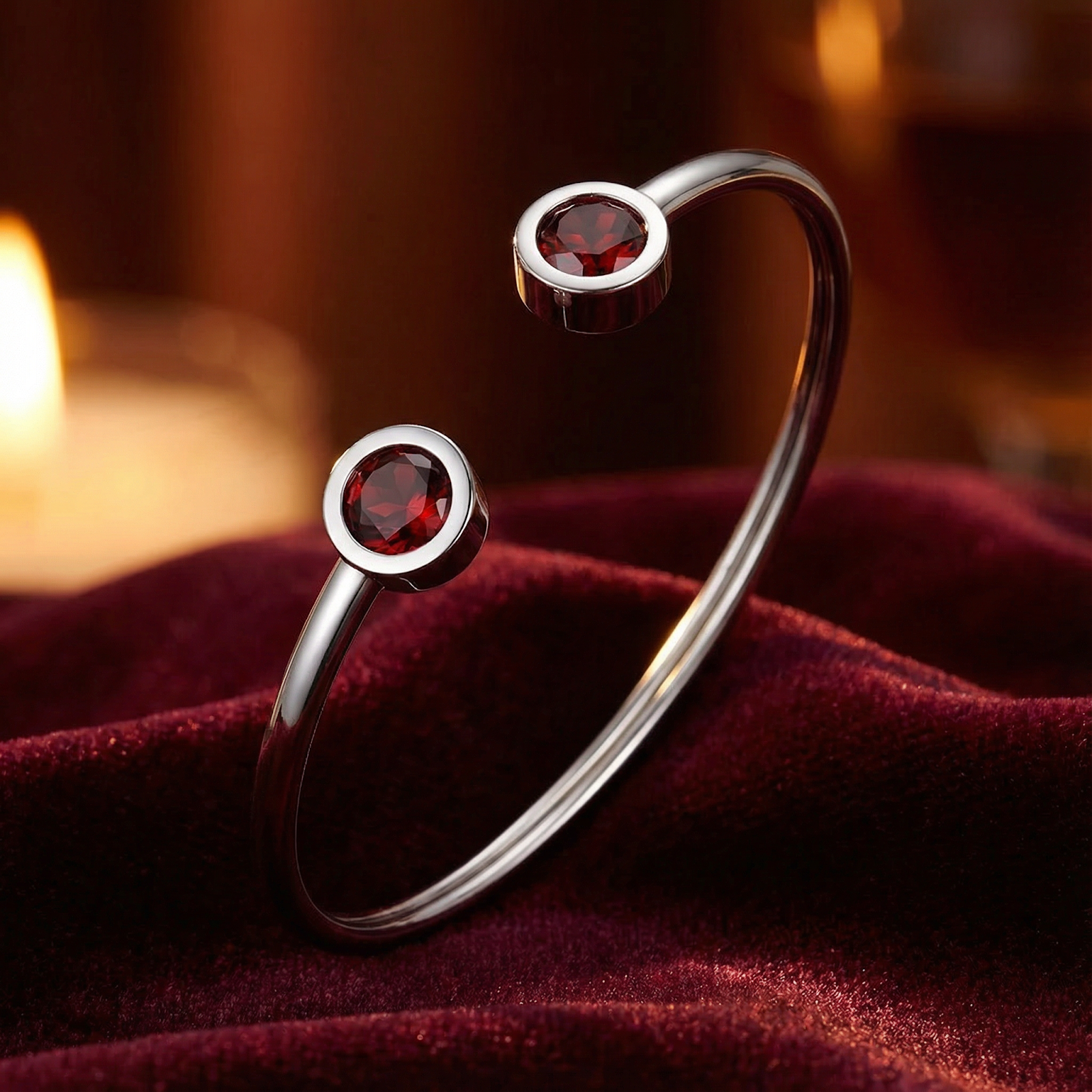 Stainless steel open cuff bracelet with round-cut simulated garnets on red velvet with warm candle light.