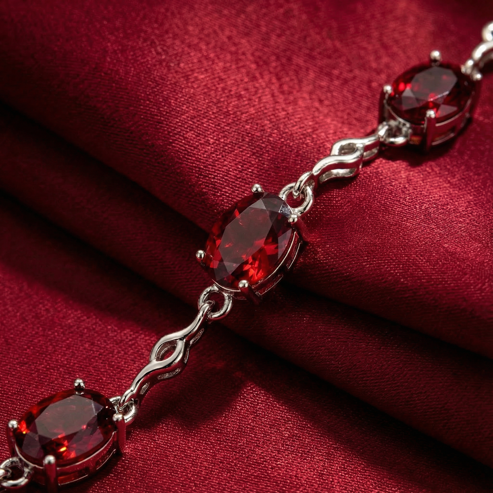 Macro view of oval-cut pigeon blood simulated rubies and silver links on the Thalira station bracelet.