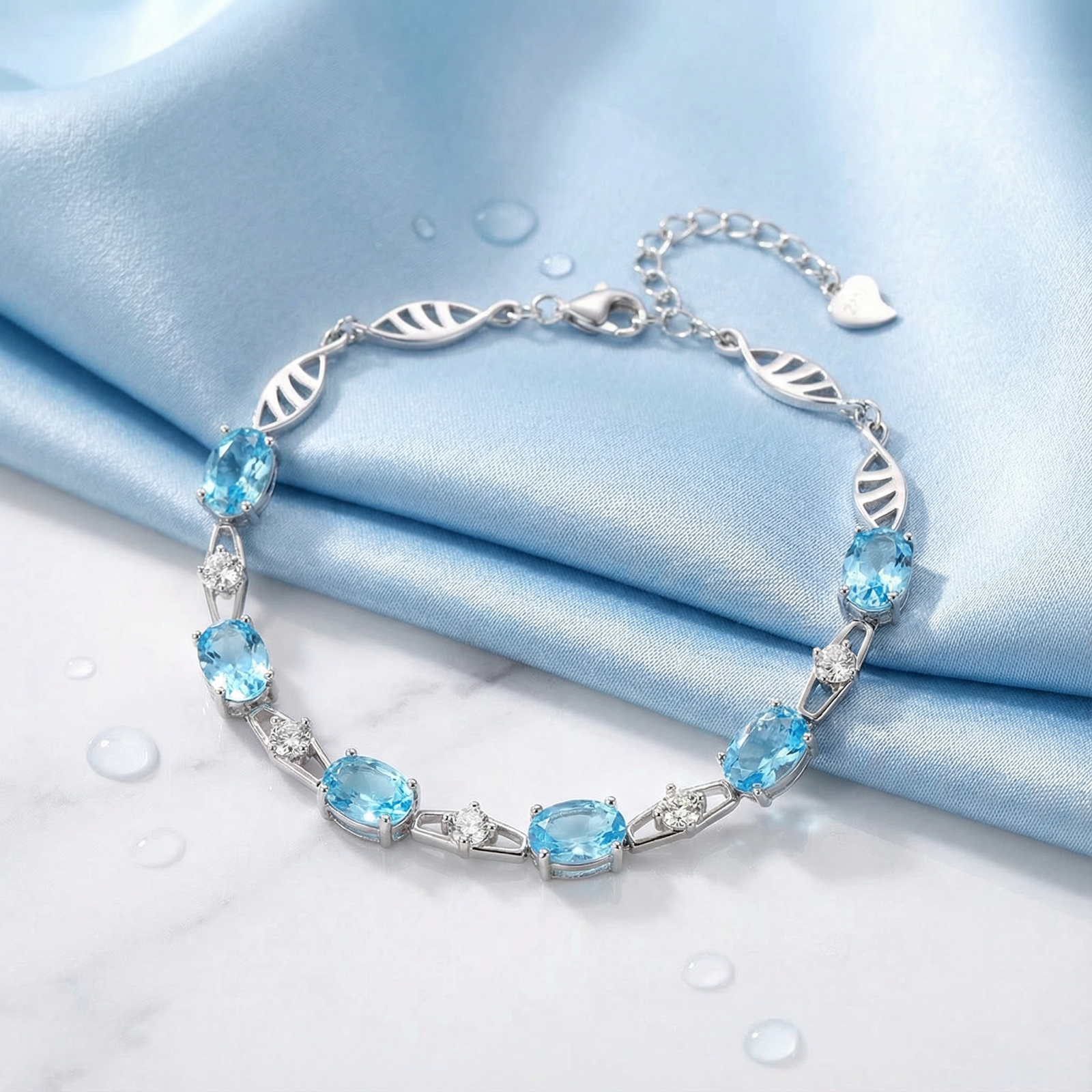 Oval cut simulated aquamarine sterling silver bracelet displayed on blue silk and marble background.