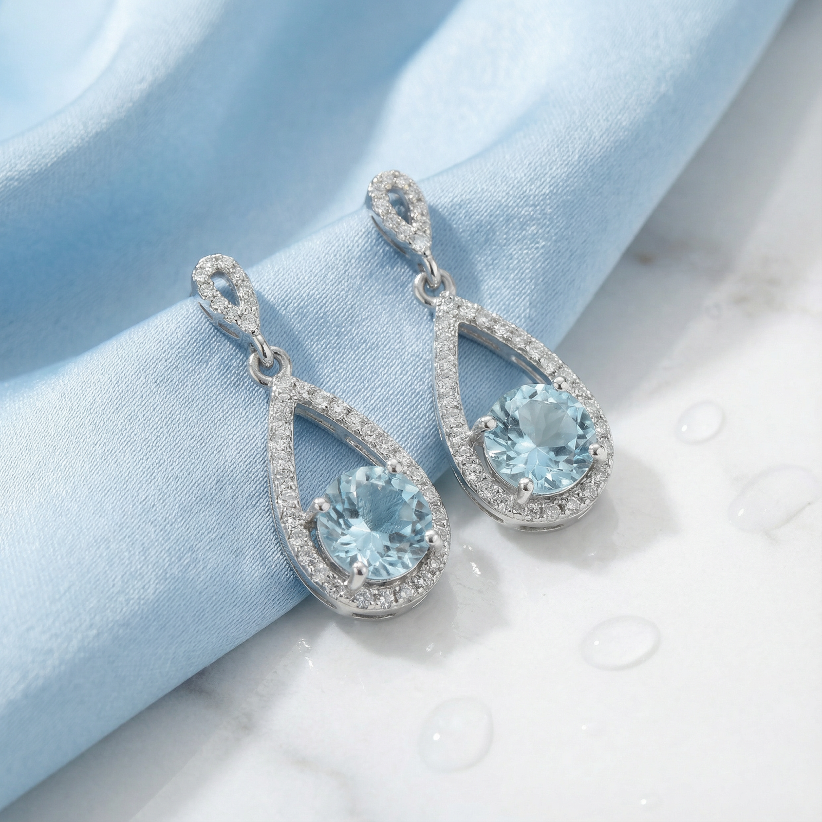 Macro view of sterling silver teardrop earrings featuring round-cut simulated aquamarine and pavé accents.