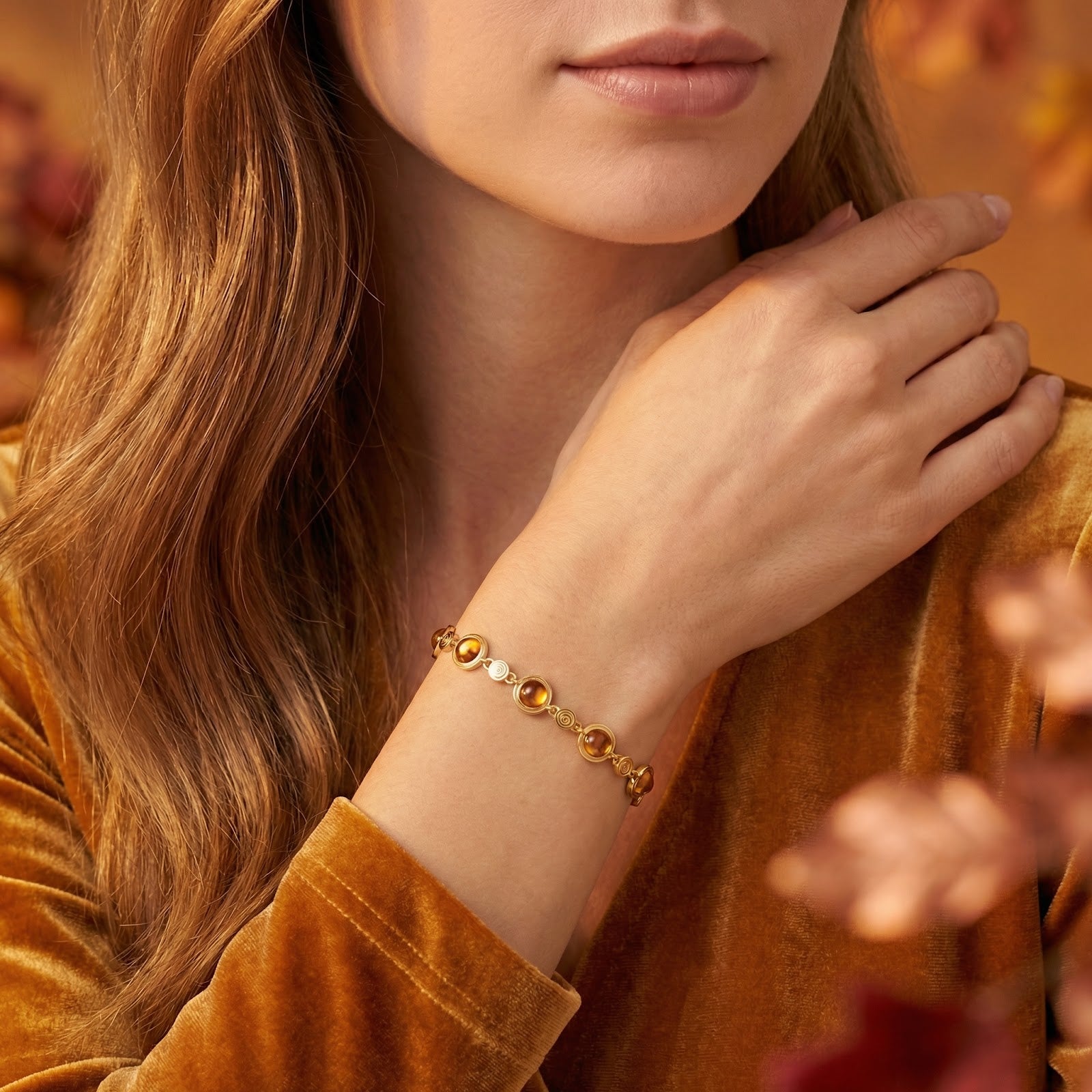 Model wearing the 18K gold vermeil Calythia station bracelet with orange simulated topaz stones on her wrist.