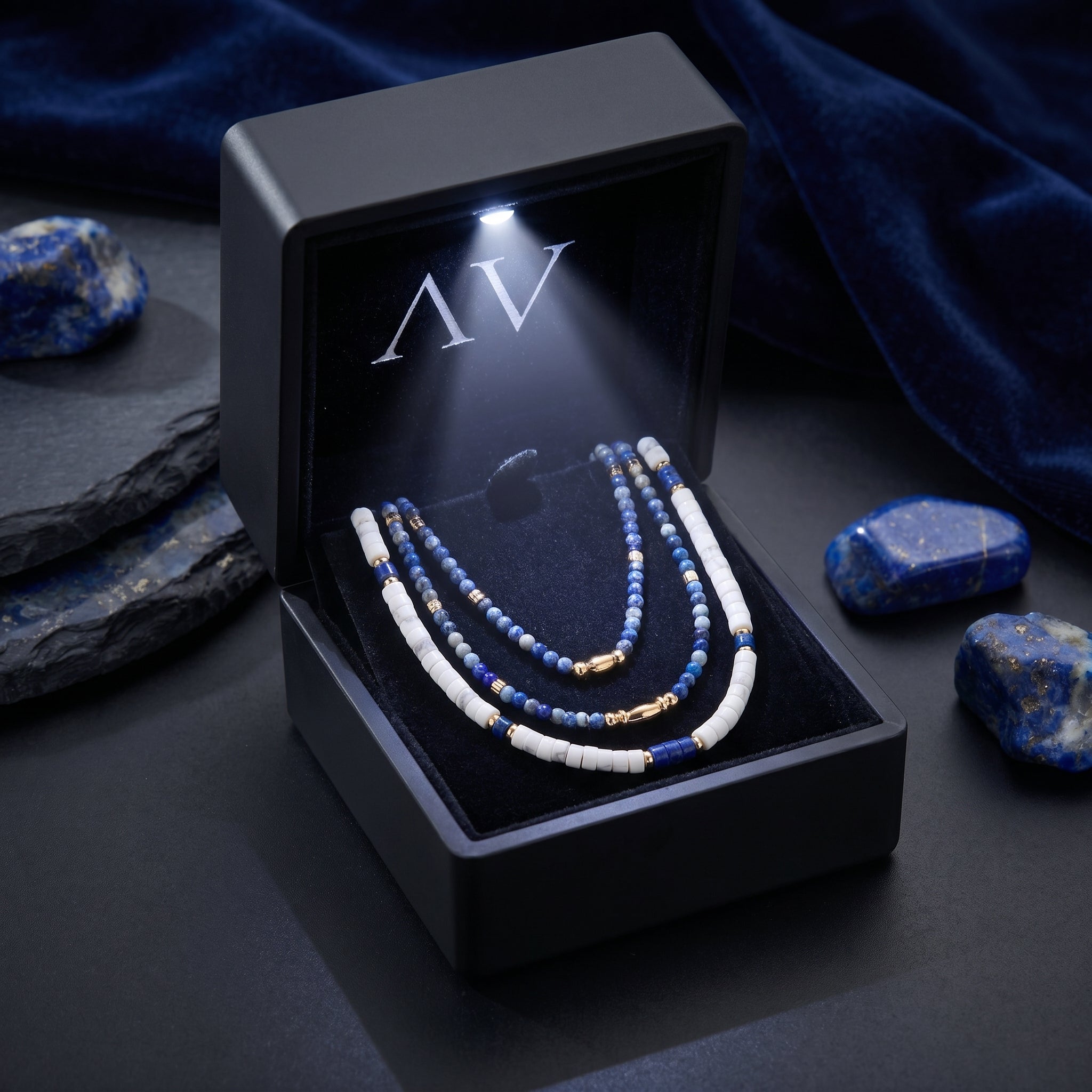 Natural lapis and white bead necklace set in a premium black LED-lit jewelry box on a dark styled background.