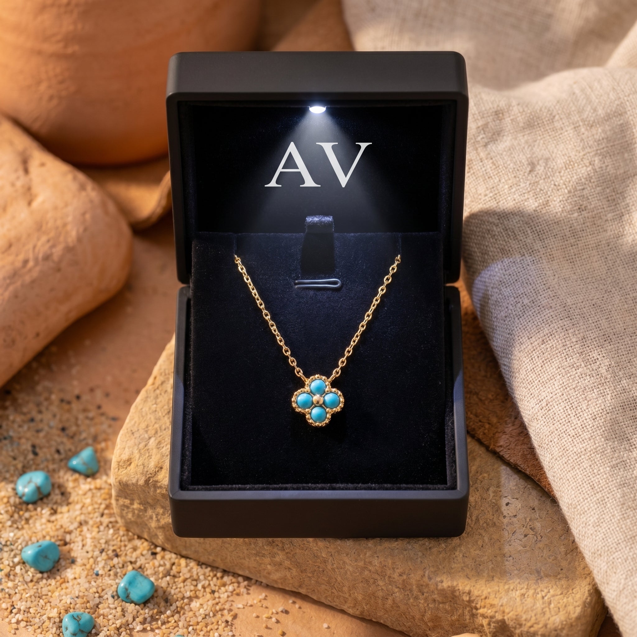 Gold turquoise flower necklace presented in a black lighted gift box on a desert-themed background.