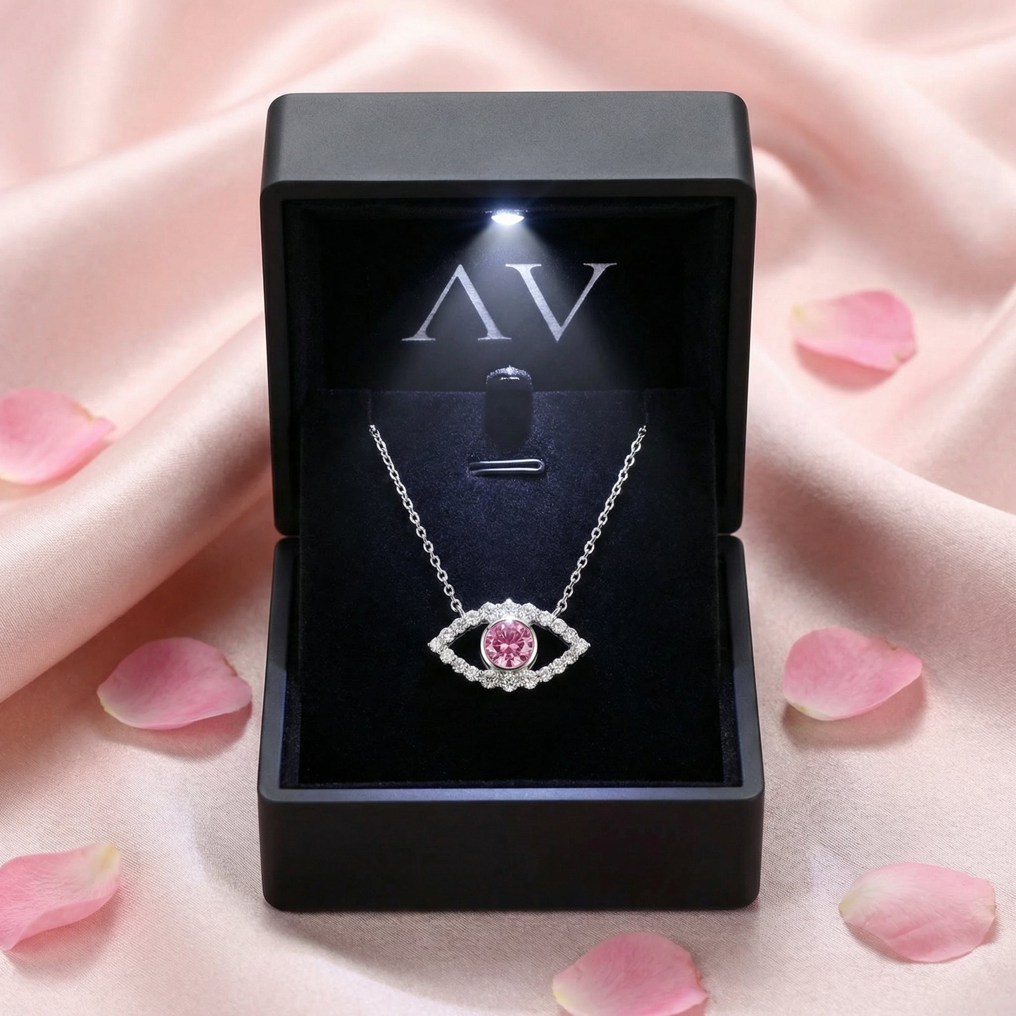 Pink moissanite eye necklace presented in a black LED-lighted jewelry box on pink satin.