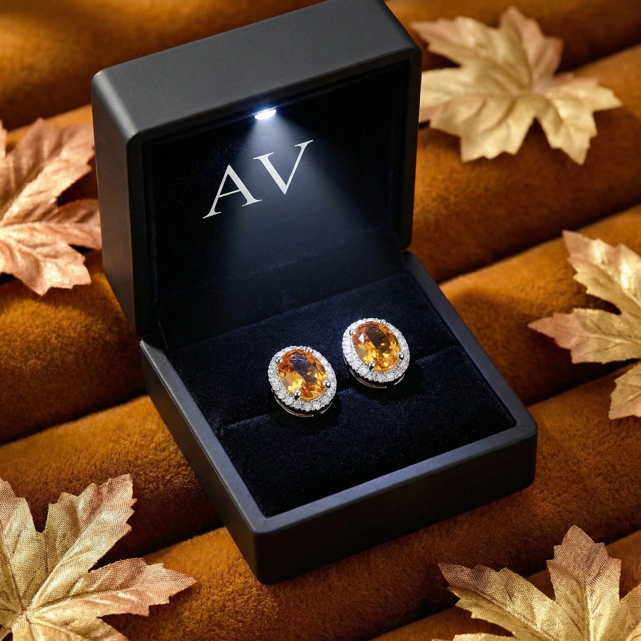Oval simulated topaz halo stud earrings in S925 sterling silver inside a black LED-lit gift box with autumn leaves.