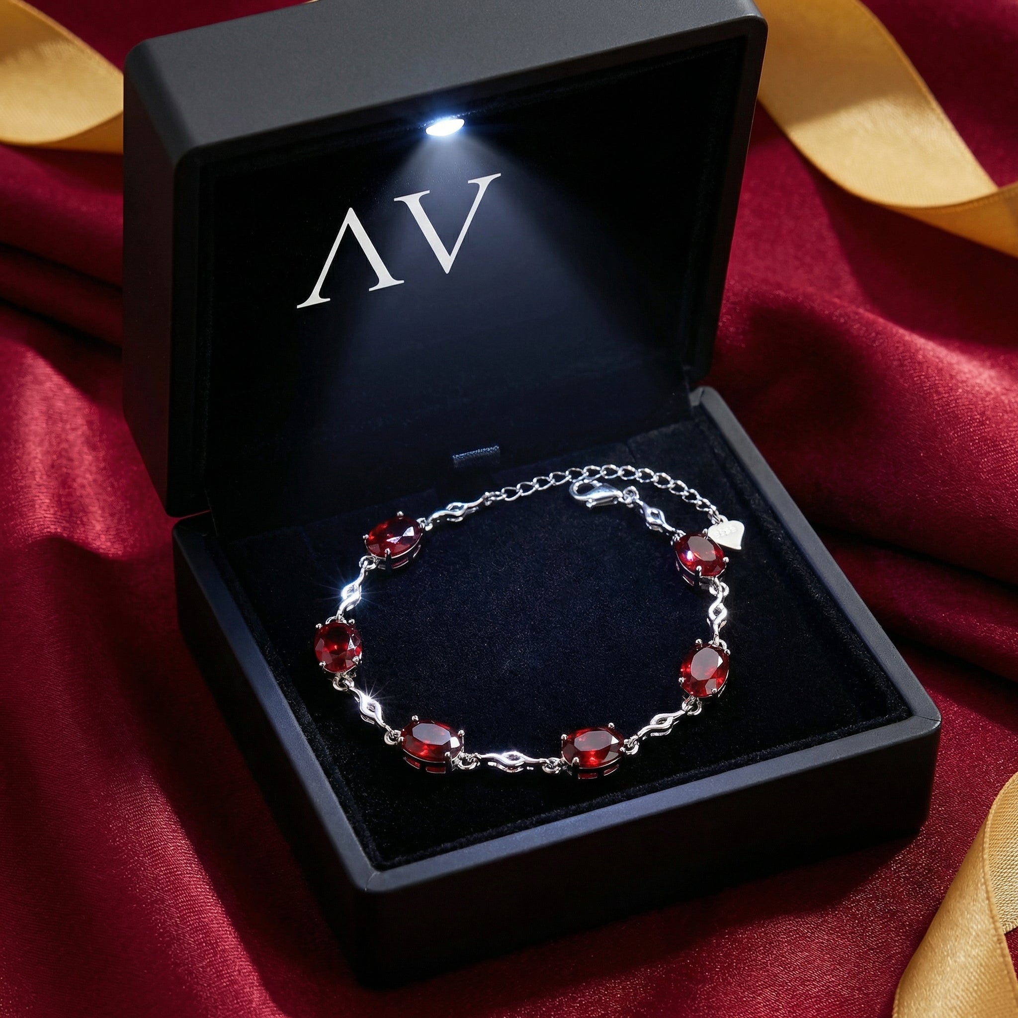 Thalira sterling silver simulated ruby bracelet in a black LED-lit gift box on red satin with a gold ribbon.