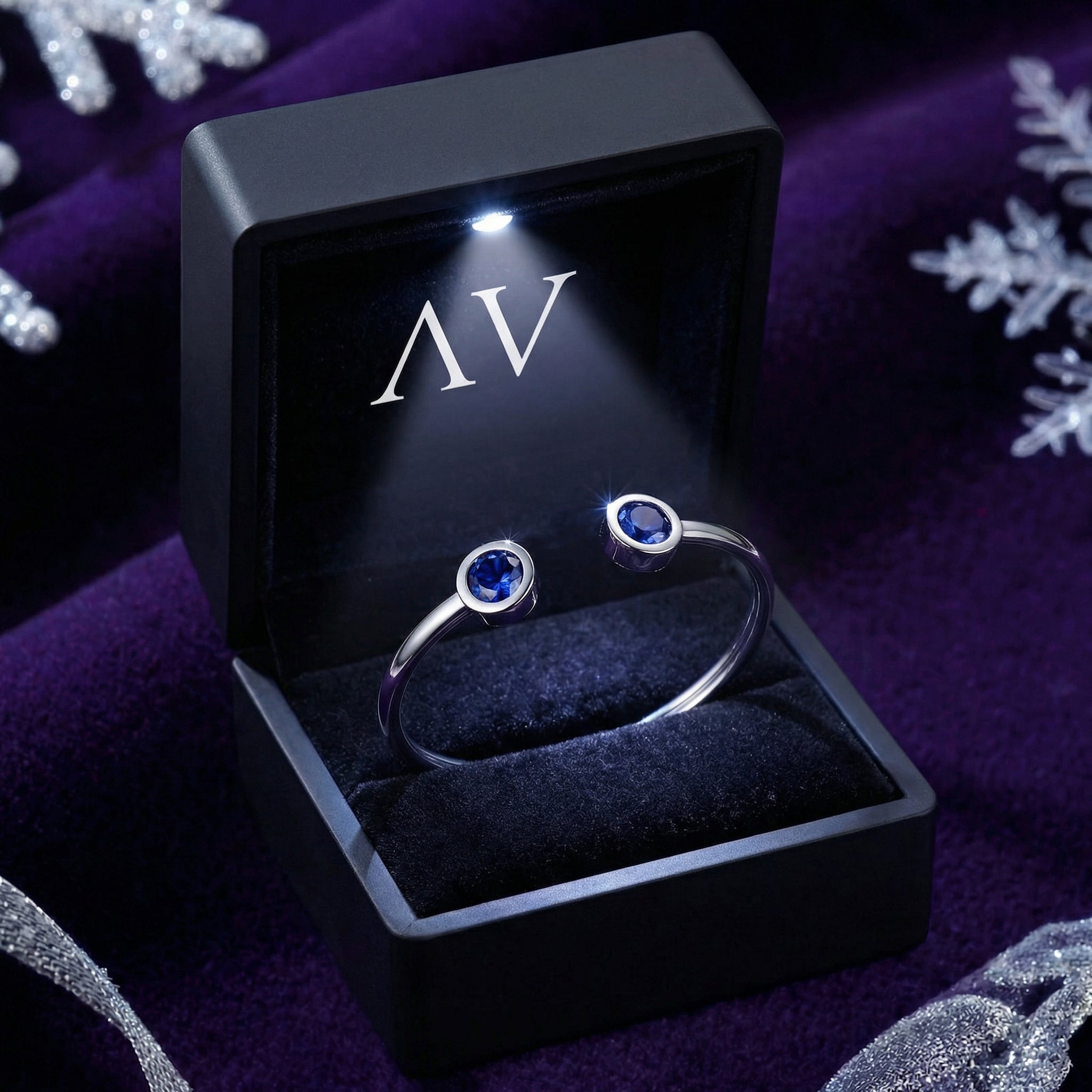 Silver Veralis cuff with simulated tanzanite stones presented in a lighted black jewelry gift box.
