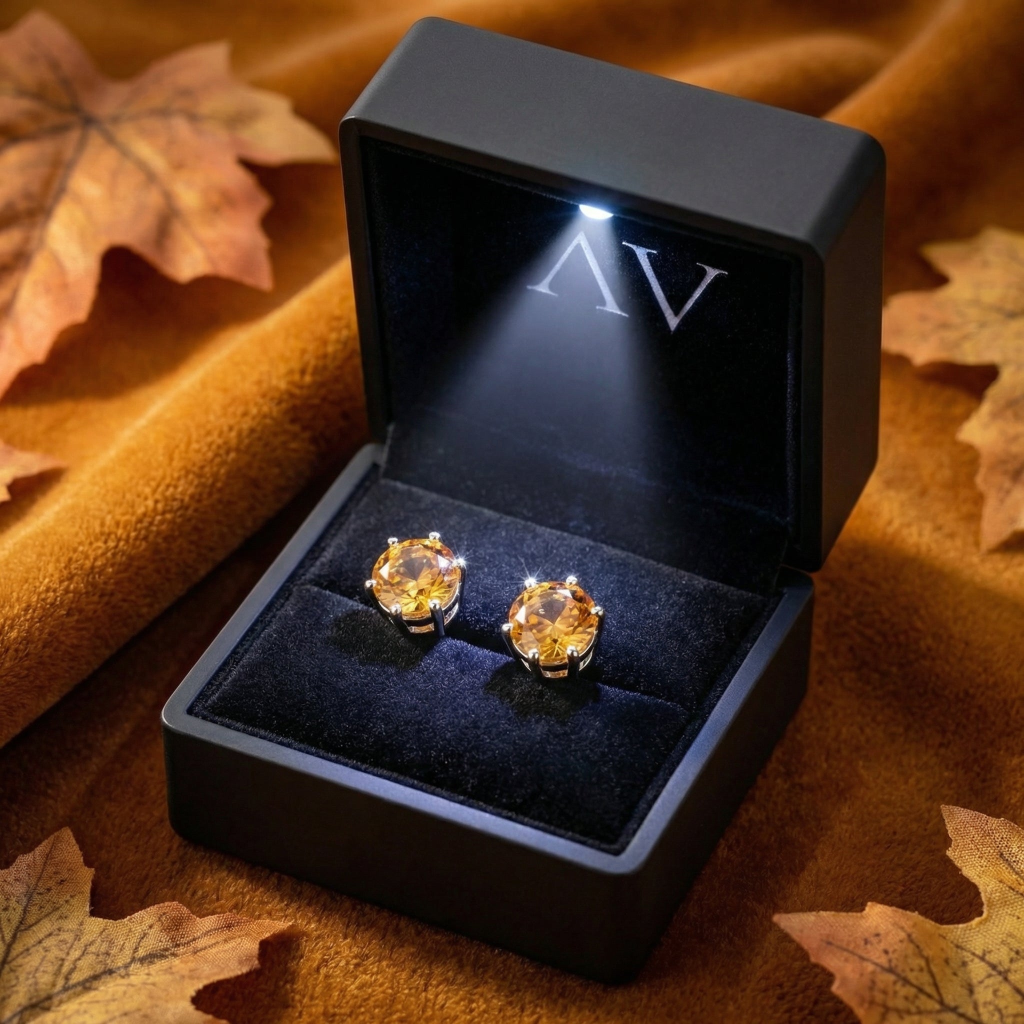 Round-cut simulated topaz sterling silver stud earrings in a lighted black gift box.