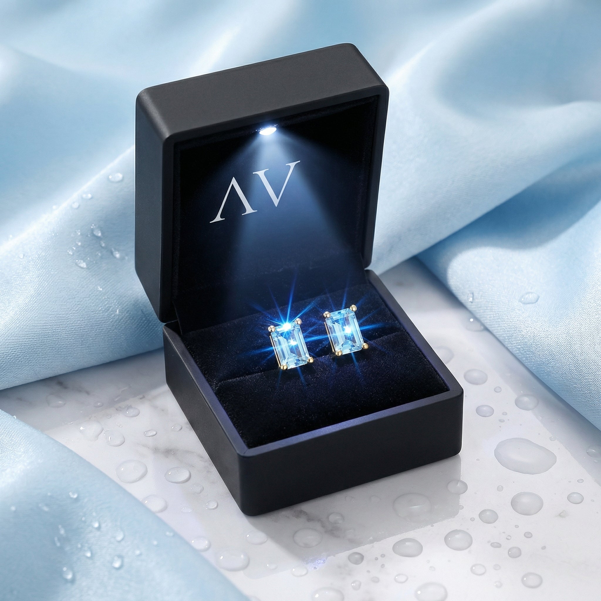 Baguette-cut simulated aquamarine gold vermeil earrings in a lighted black jewelry presentation box.