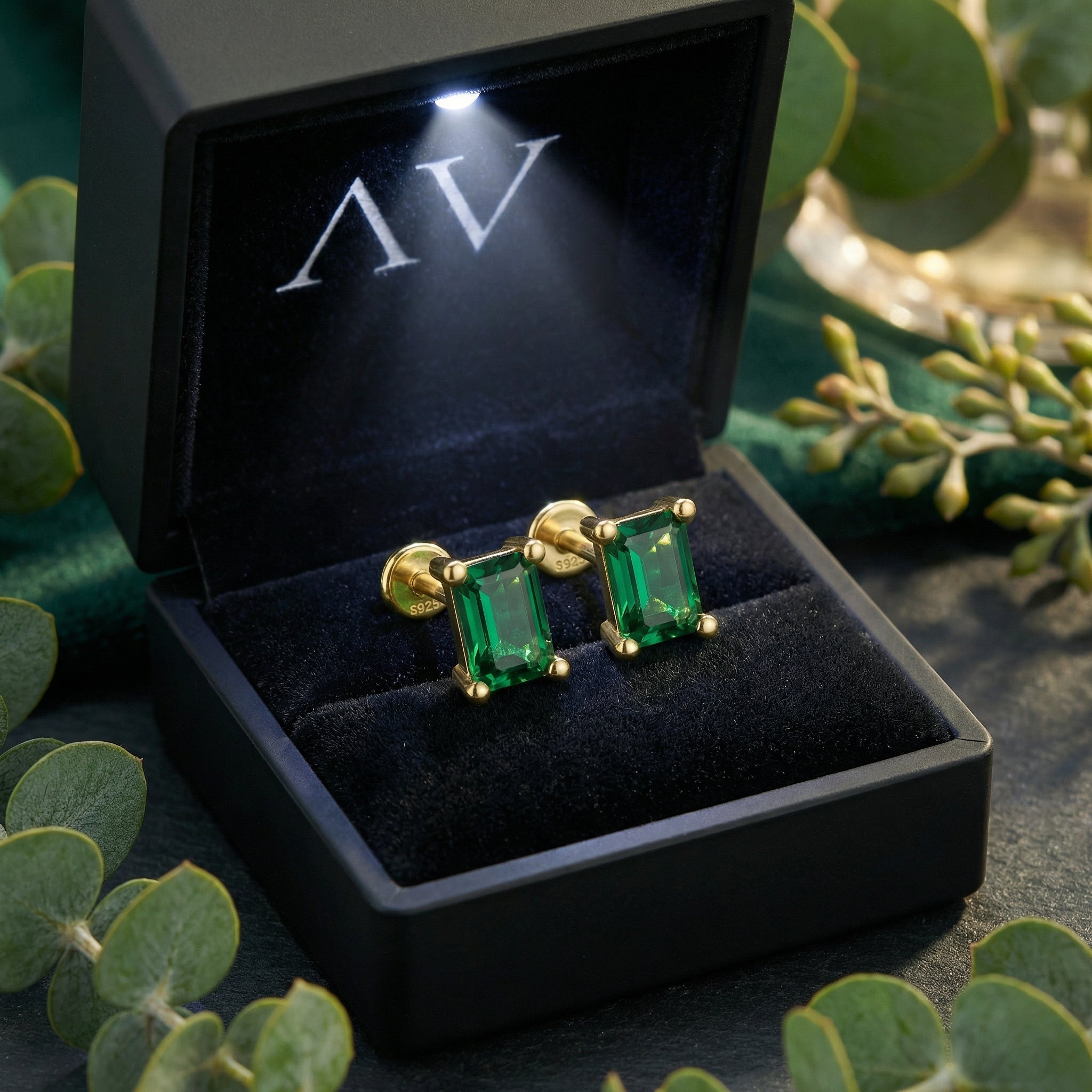 Emerald cut simulated emerald stud earrings in 18K gold vermeil inside a black LED-lighted jewelry box.