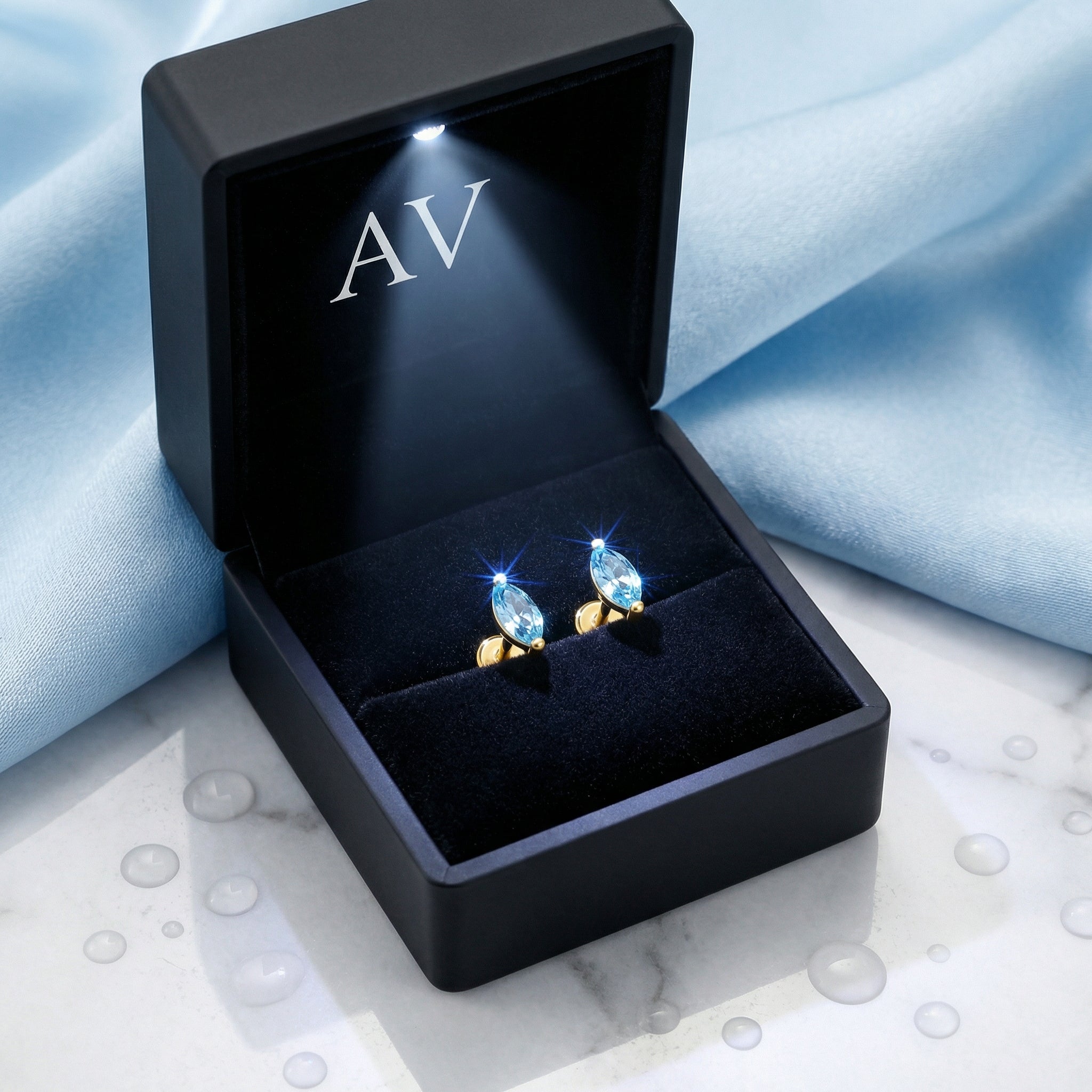 Marquise cut simulated aquamarine gold earrings inside a black LED-lit jewelry presentation box.