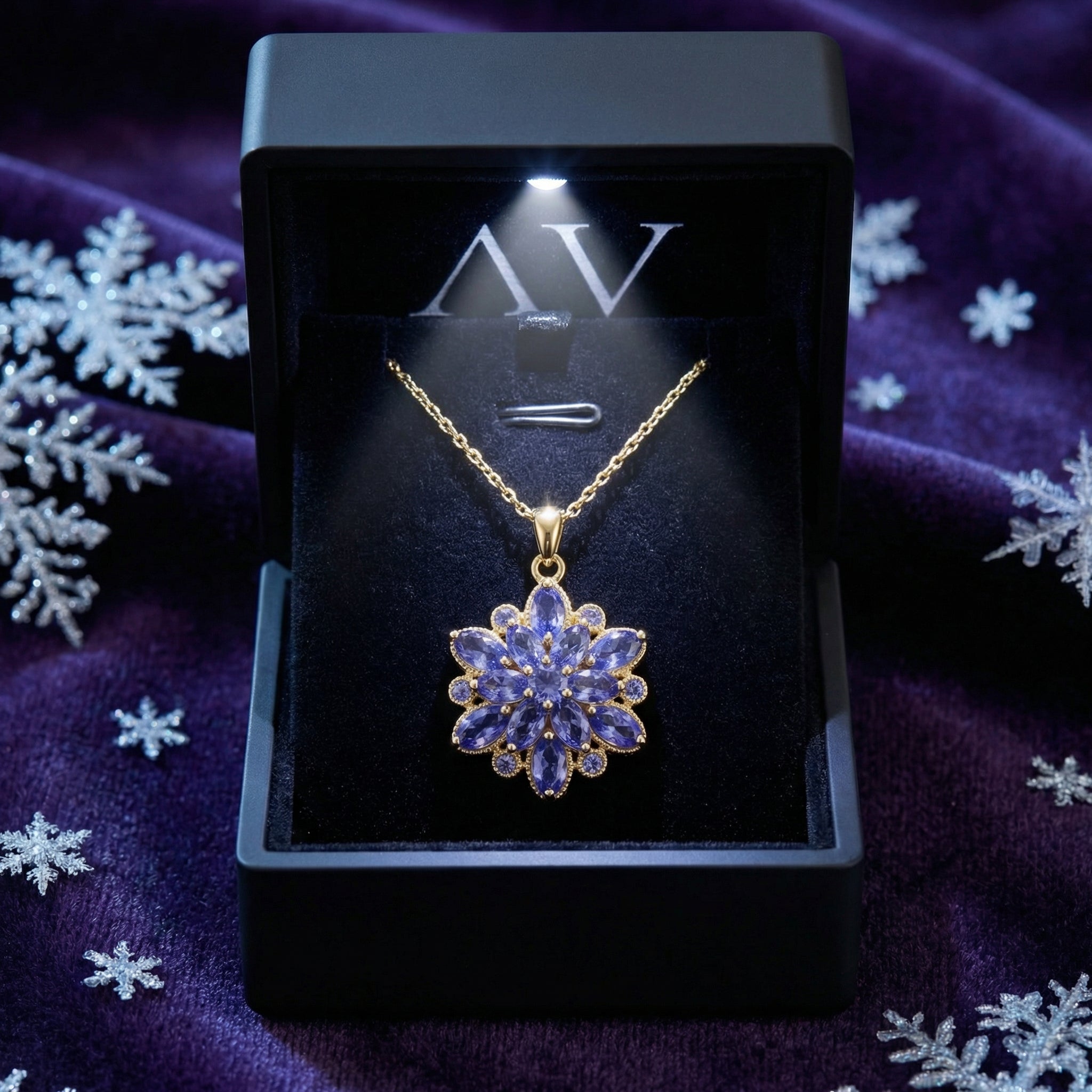 Gold finish stainless steel tanzanite necklace in a black LED-lighted gift box on a purple velvet background.