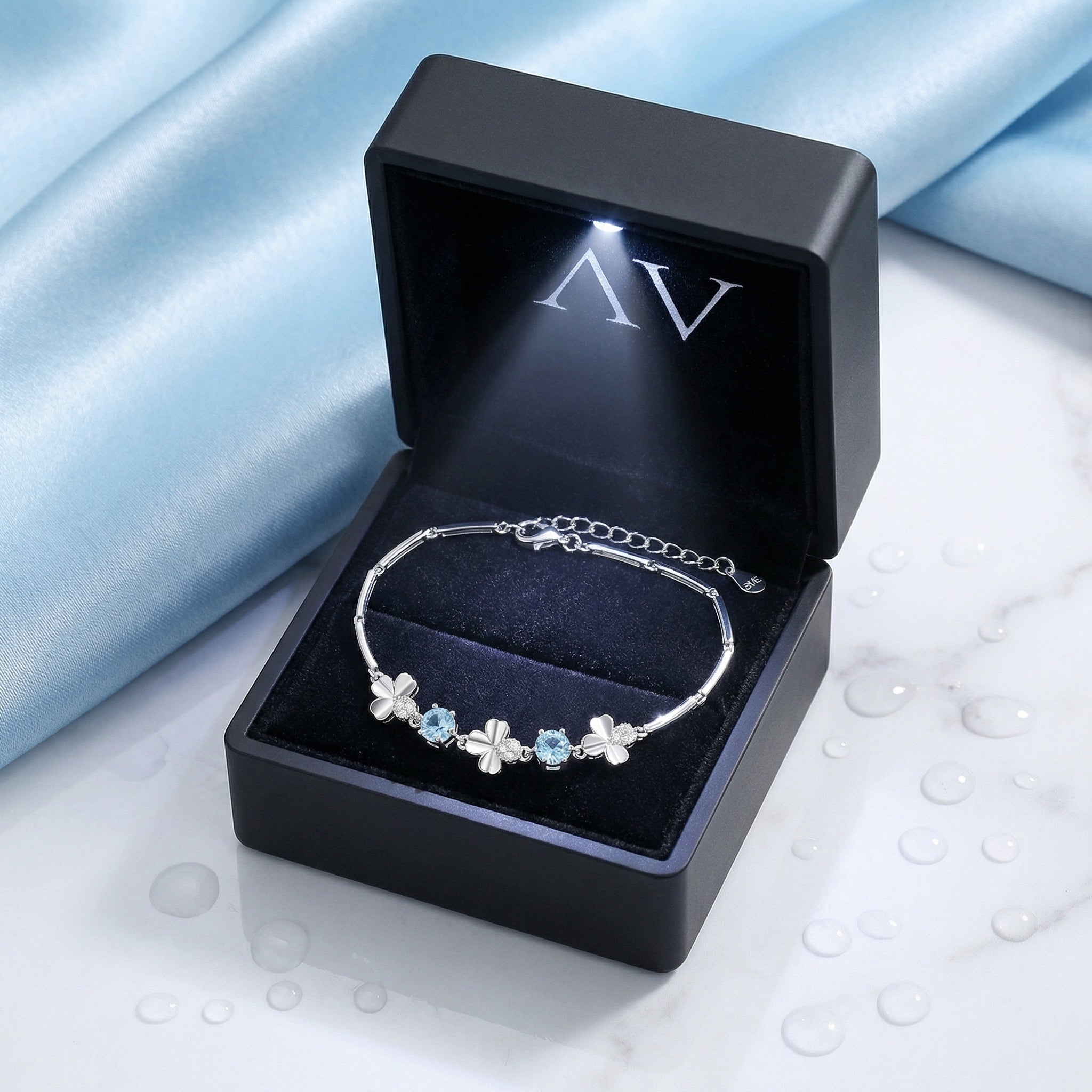 Sterling silver March birthstone station bracelet presented in a premium black LED-lit jewelry gift box.