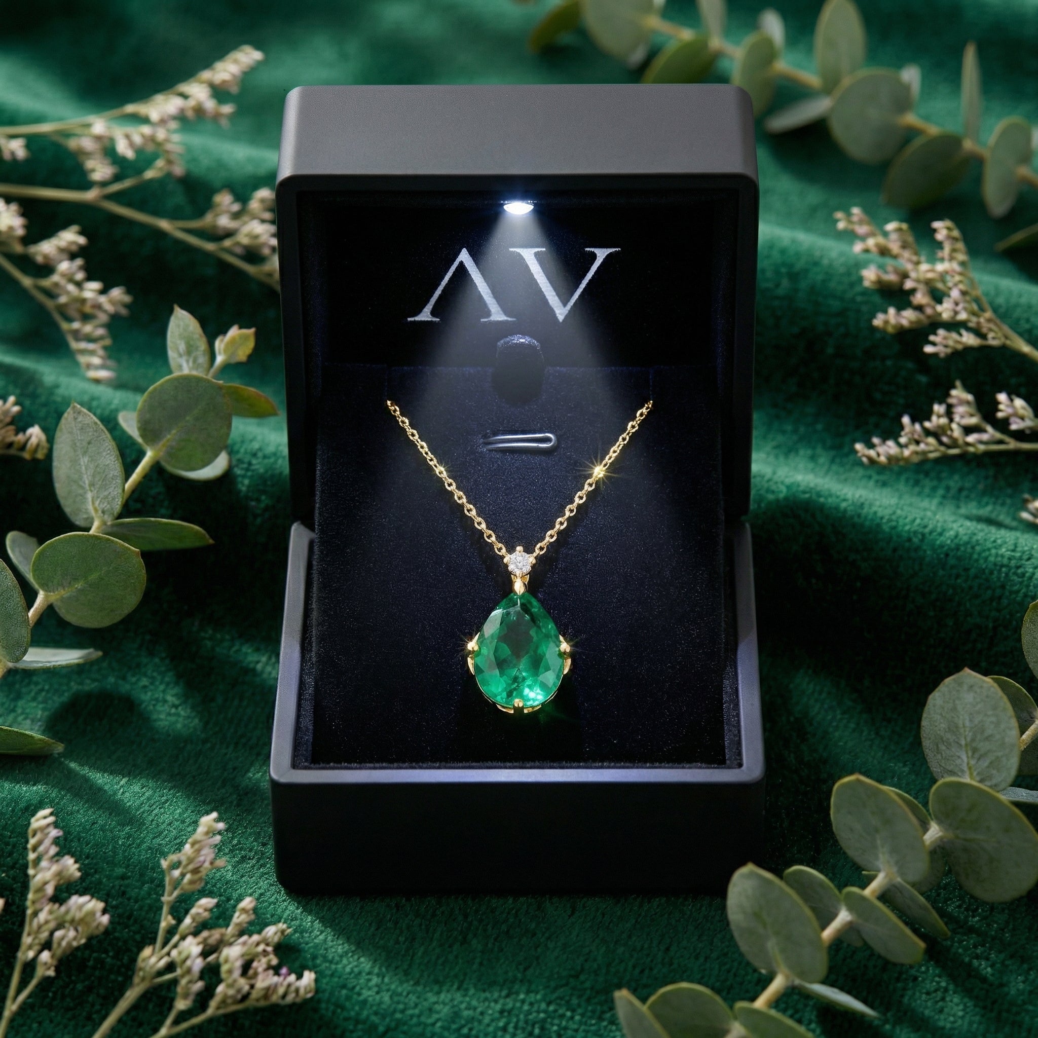 Pear cut simulated emerald necklace presented in a lighted black jewelry box on green velvet.