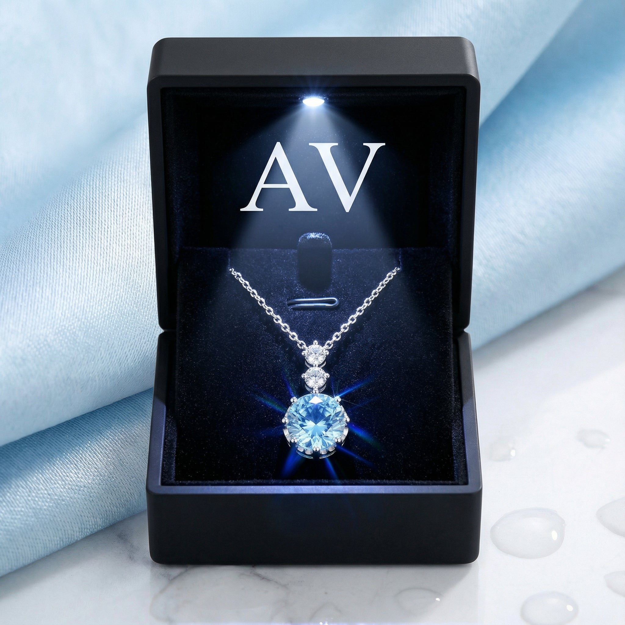Sterling silver simulated aquamarine necklace inside a black LED-lit jewelry gift box on a blue silk background.
