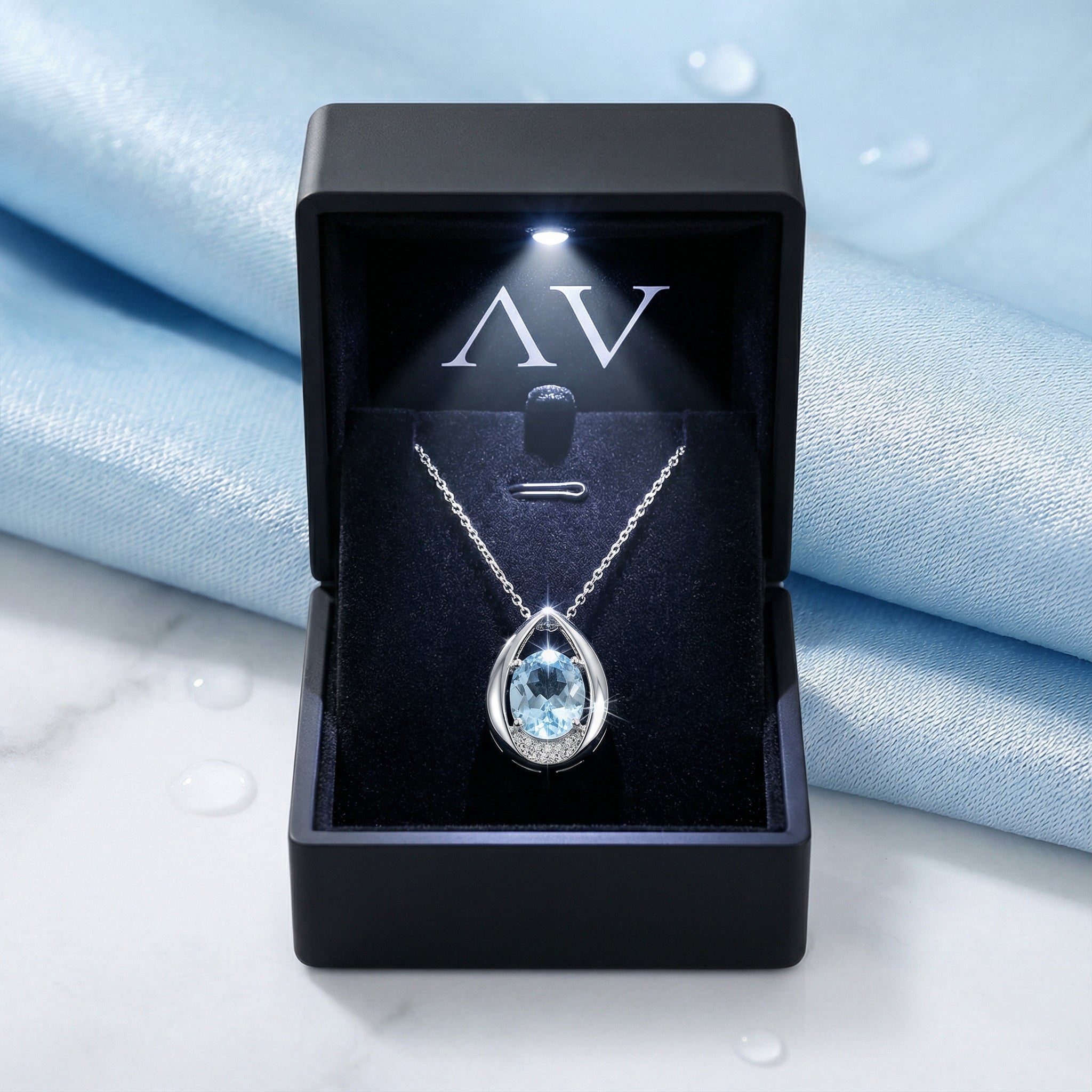 Sterling silver teardrop necklace with a blue simulated aquamarine inside a black LED-lit jewelry gift box.