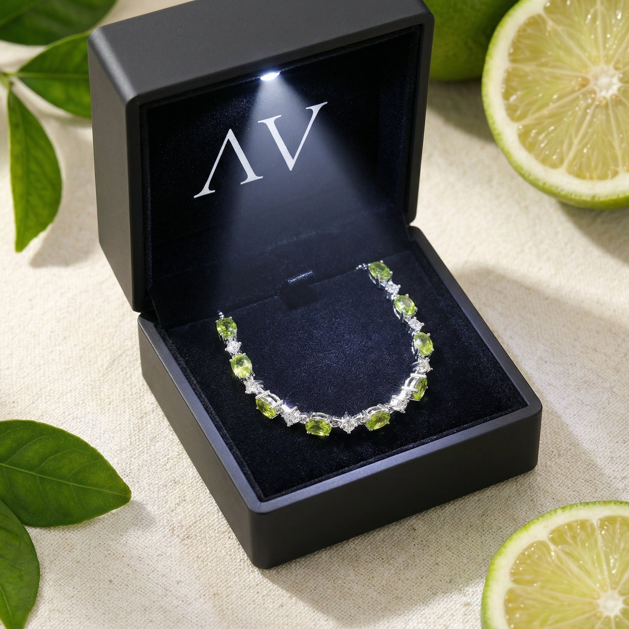 Sterling silver peridot station bracelet presented in a black LED-lit jewelry gift box with lifestyle accents.