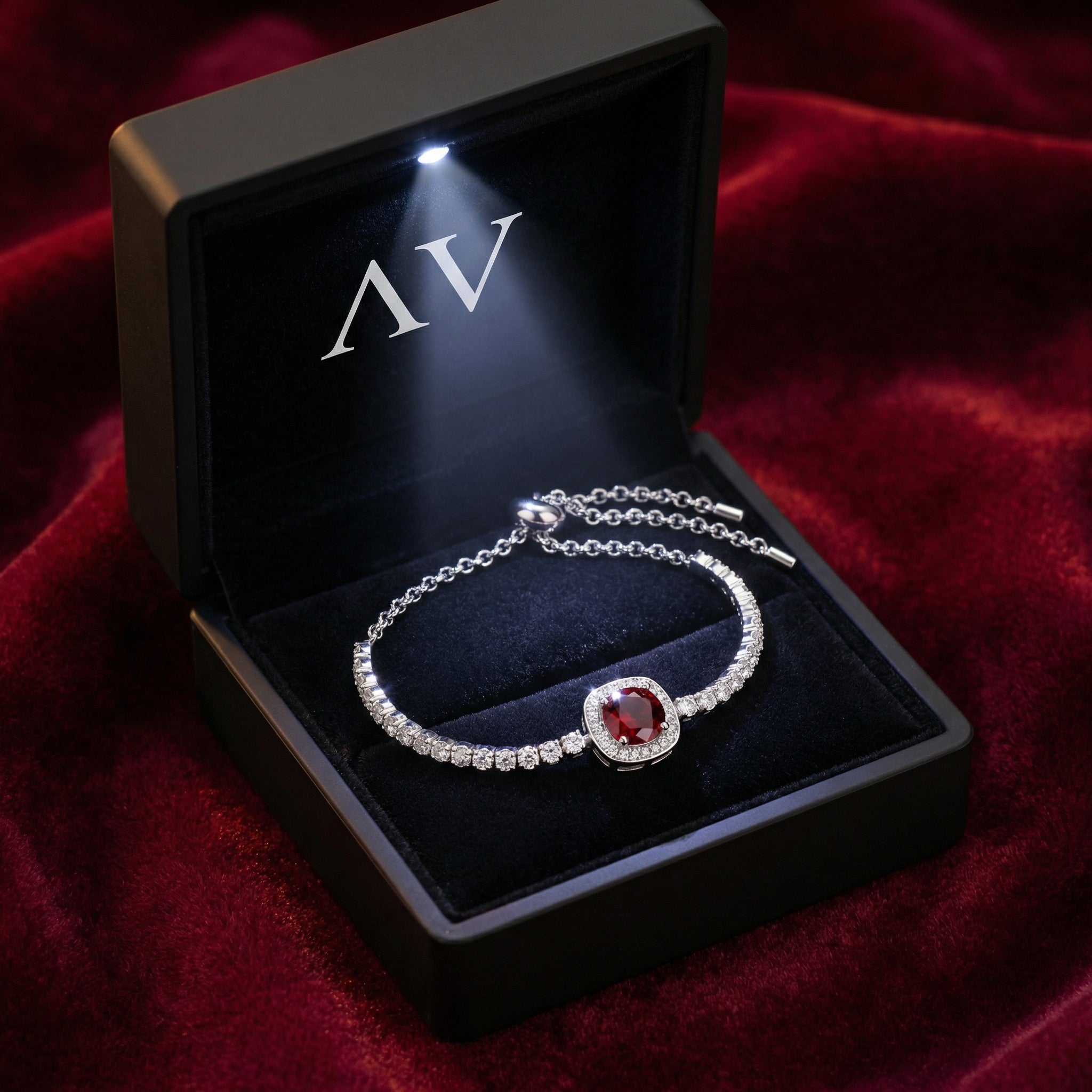 Sterling silver red garnet halo bracelet inside a black lighted jewelry box on red velvet.