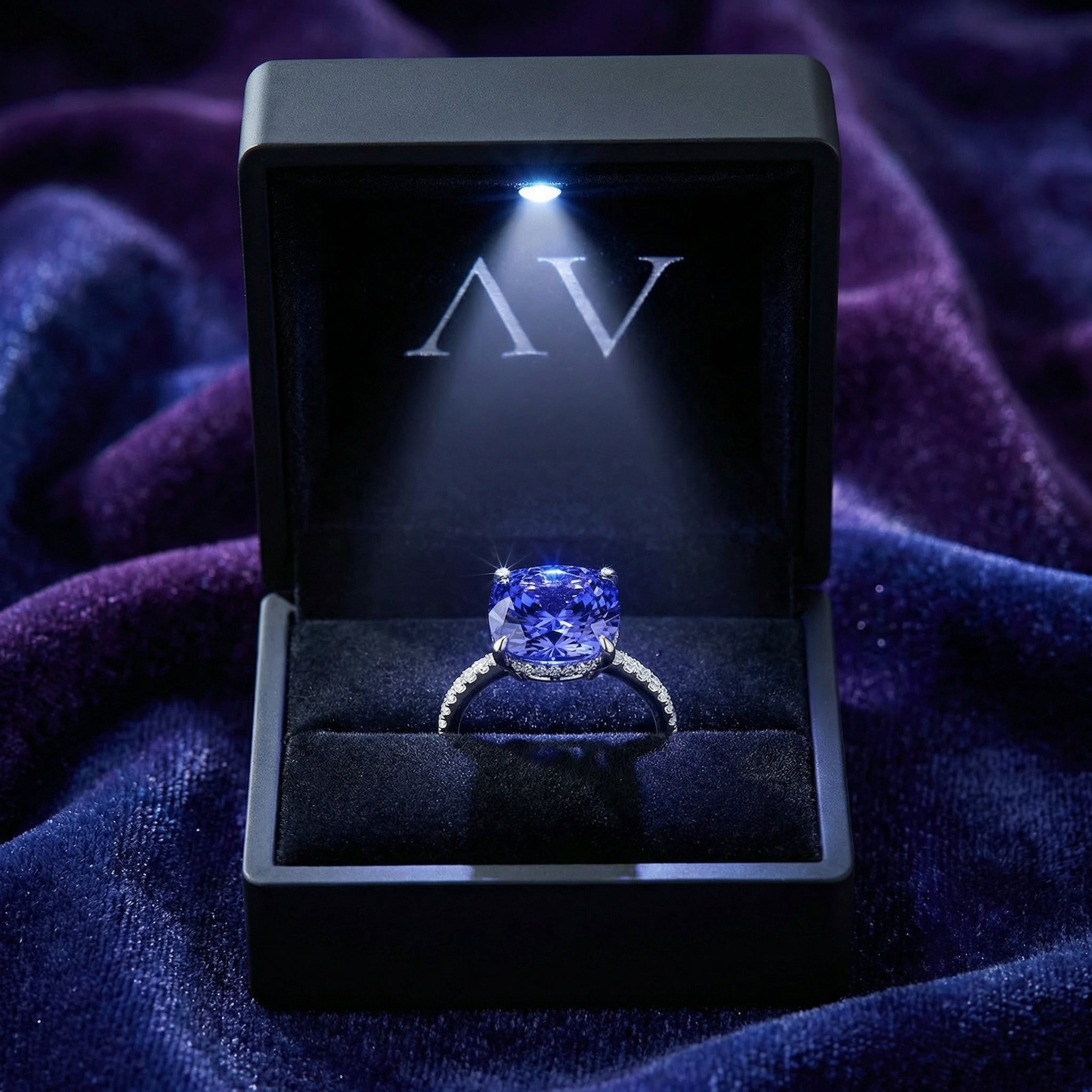 Cushion-cut simulated tanzanite S925 sterling silver ring in a lighted black jewelry box.