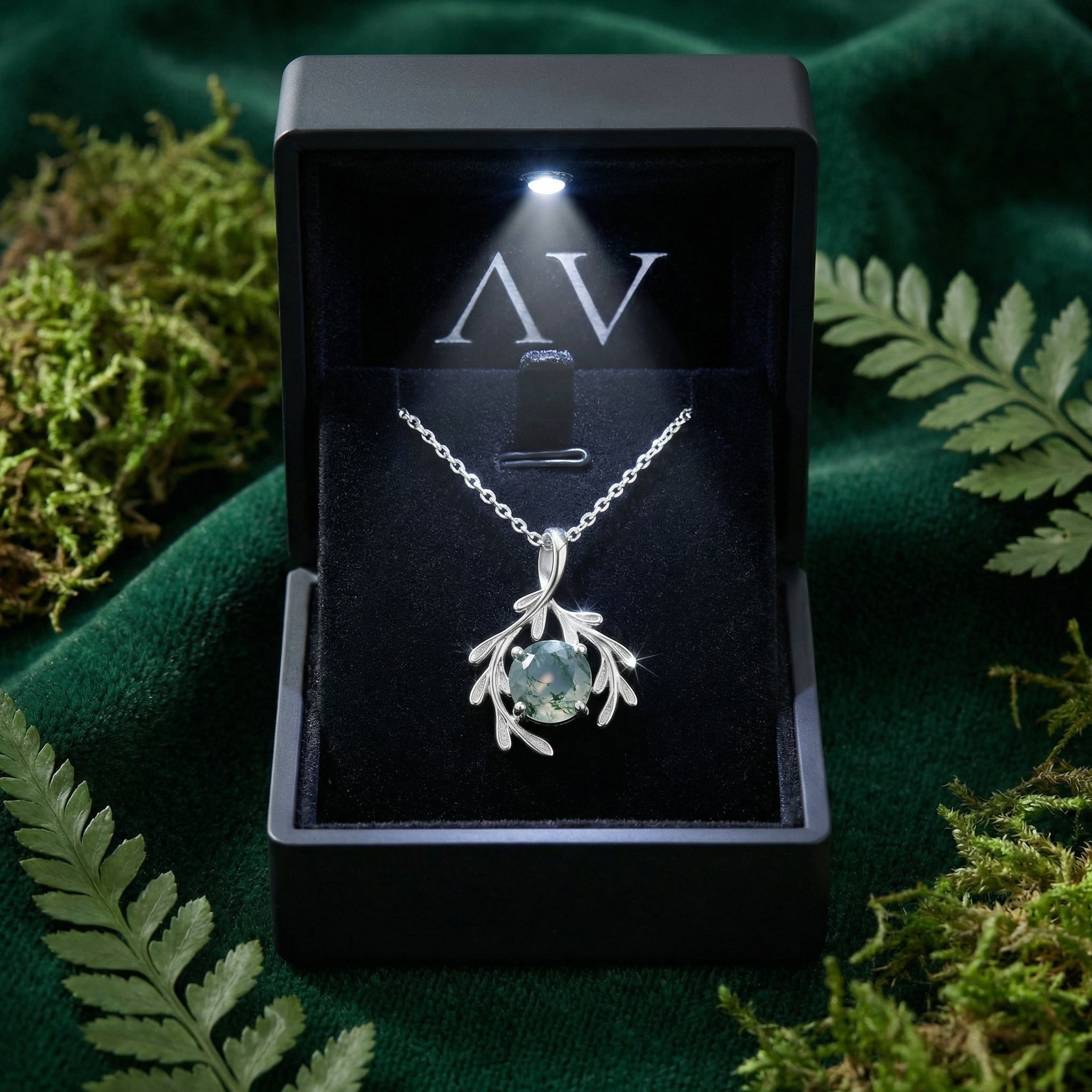 Sterling silver moss agate pendant necklace presented in a black LED-lit gift box on green velvet.