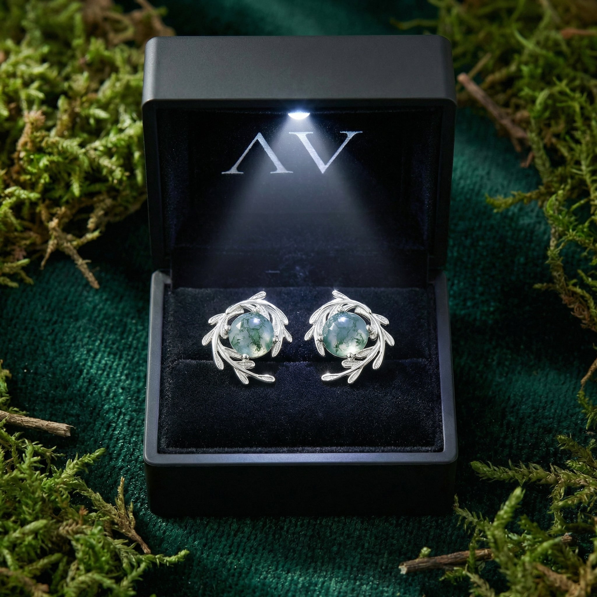 Sterling silver moss agate vine wrap stud earrings inside a black lighted gift box on a bed of moss.