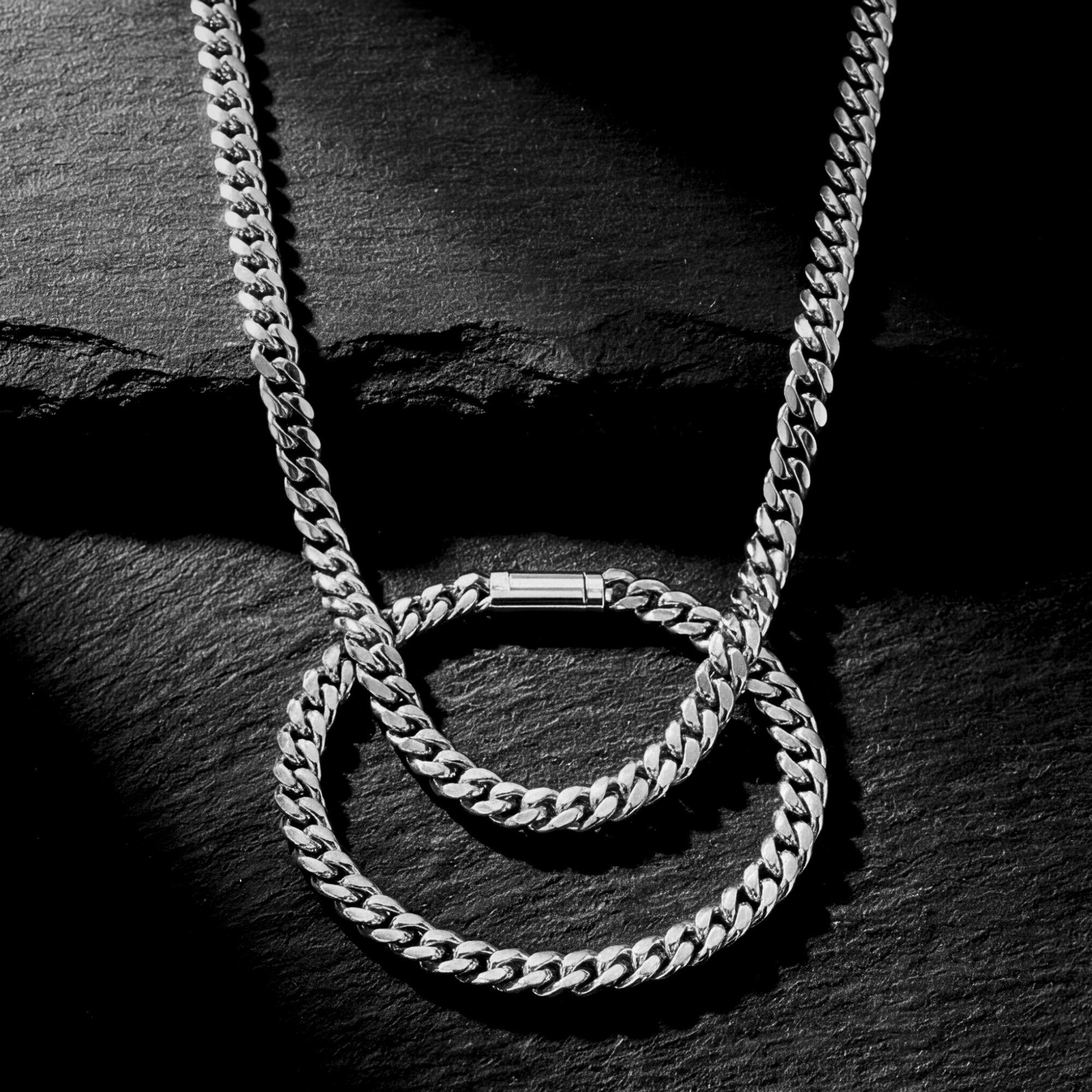 6mm silver stainless steel Cuban link chain and bracelet set on a dark textured stone background.