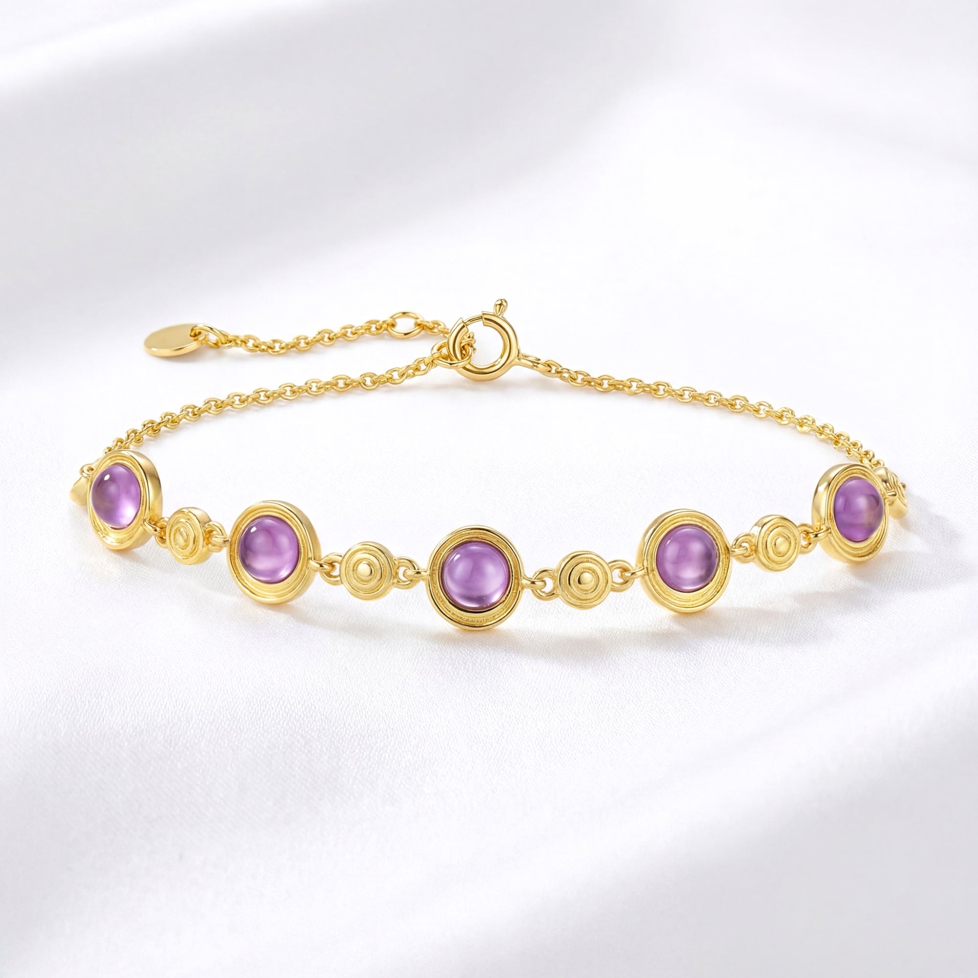 18K gold vermeil station bracelet with round cut simulated amethyst stones on a white fabric background.