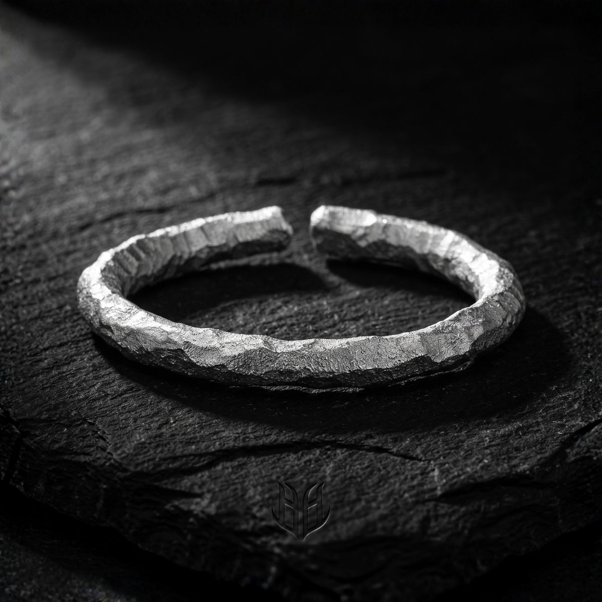 Chiseled 999 fine silver open ring lying on a dark textured slate surface.
